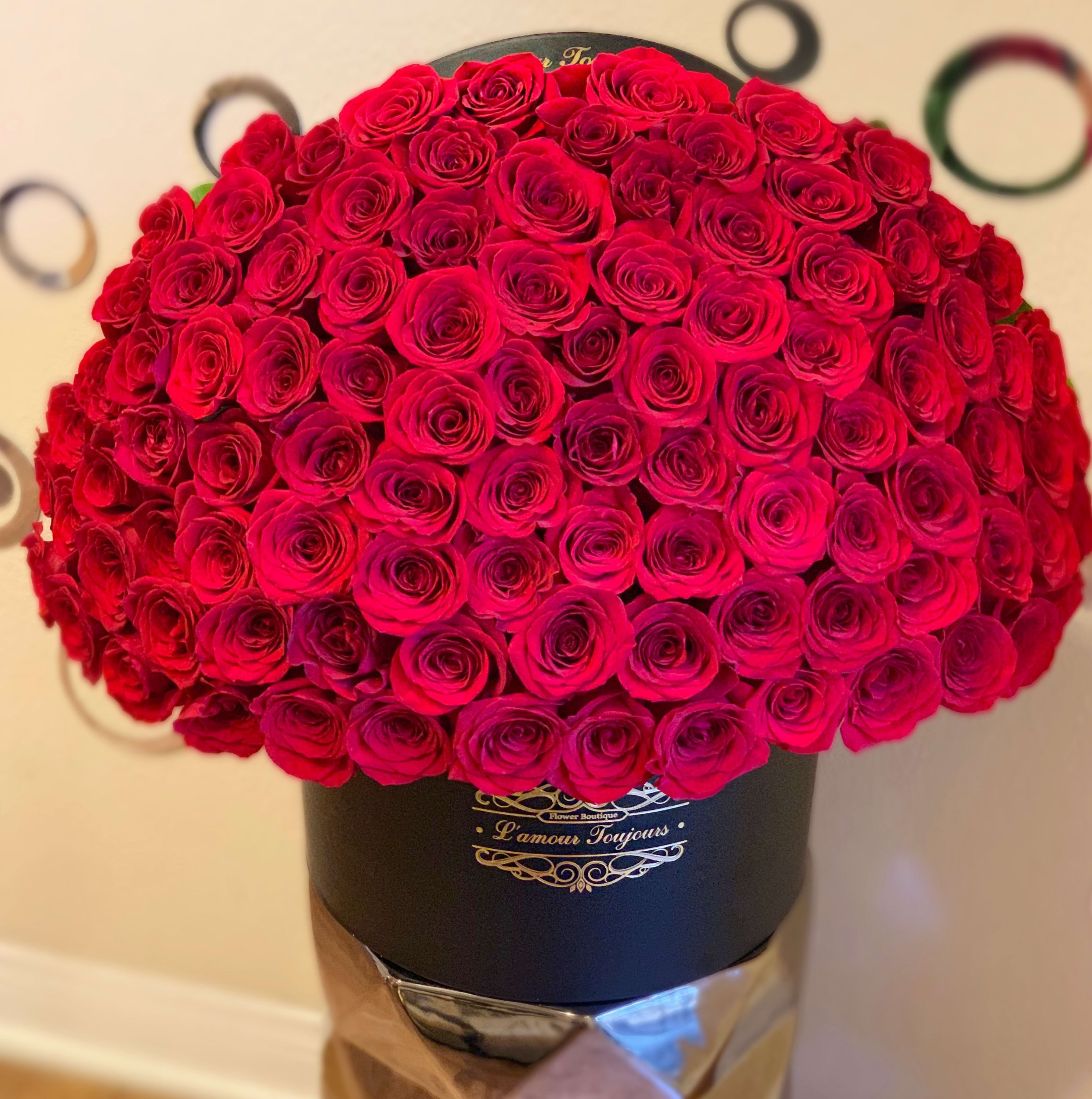 Large dome of red roses arranged tightly in a black hat box