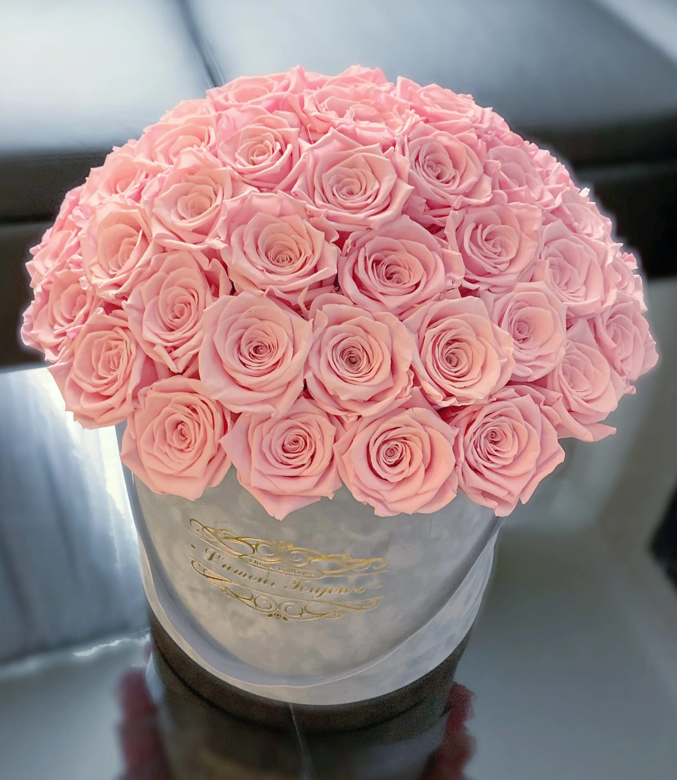 Round bouquet of pale pink roses in a gray hatbox