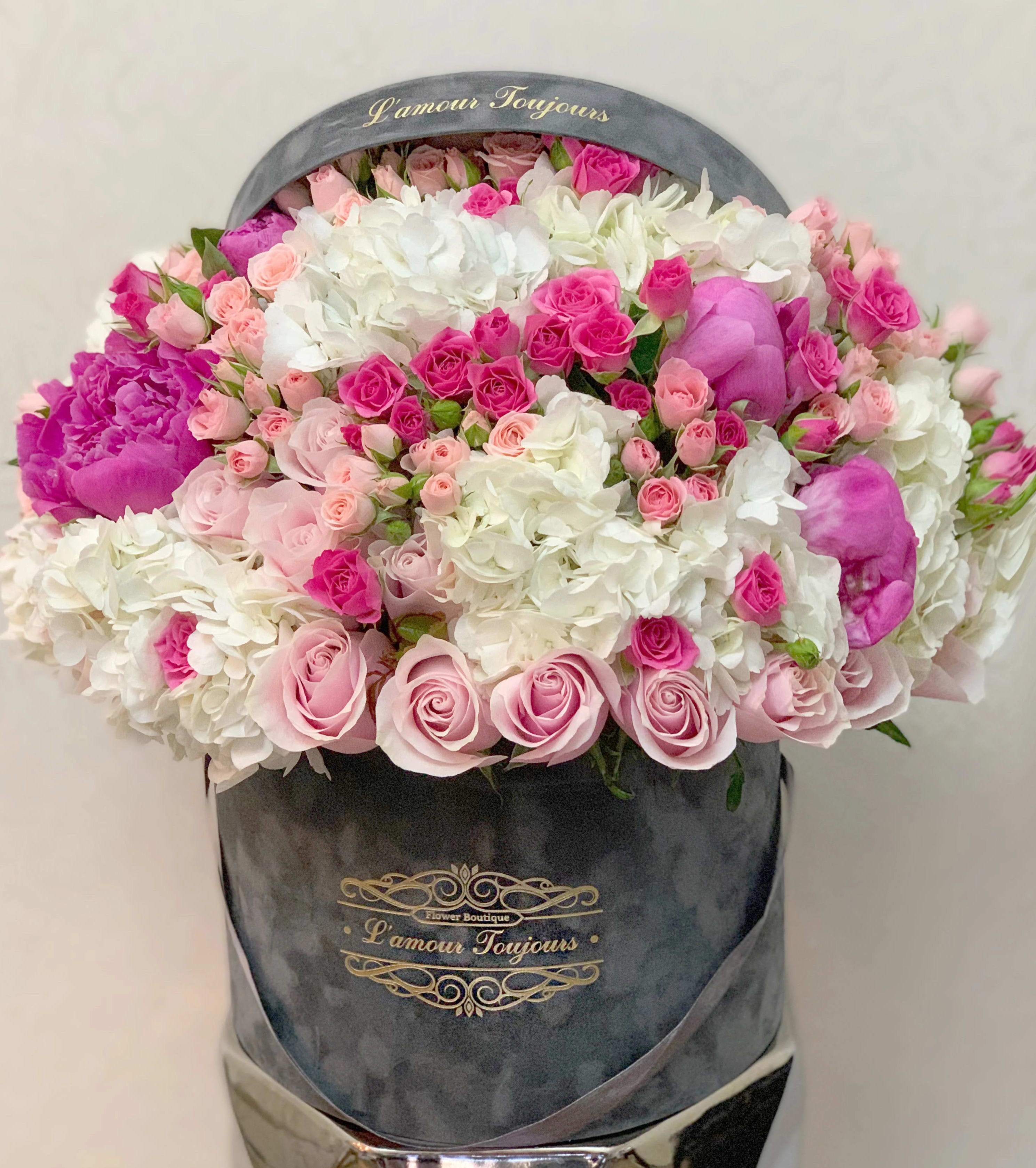 Large bouquet of pink and white roses in a gray hatbox