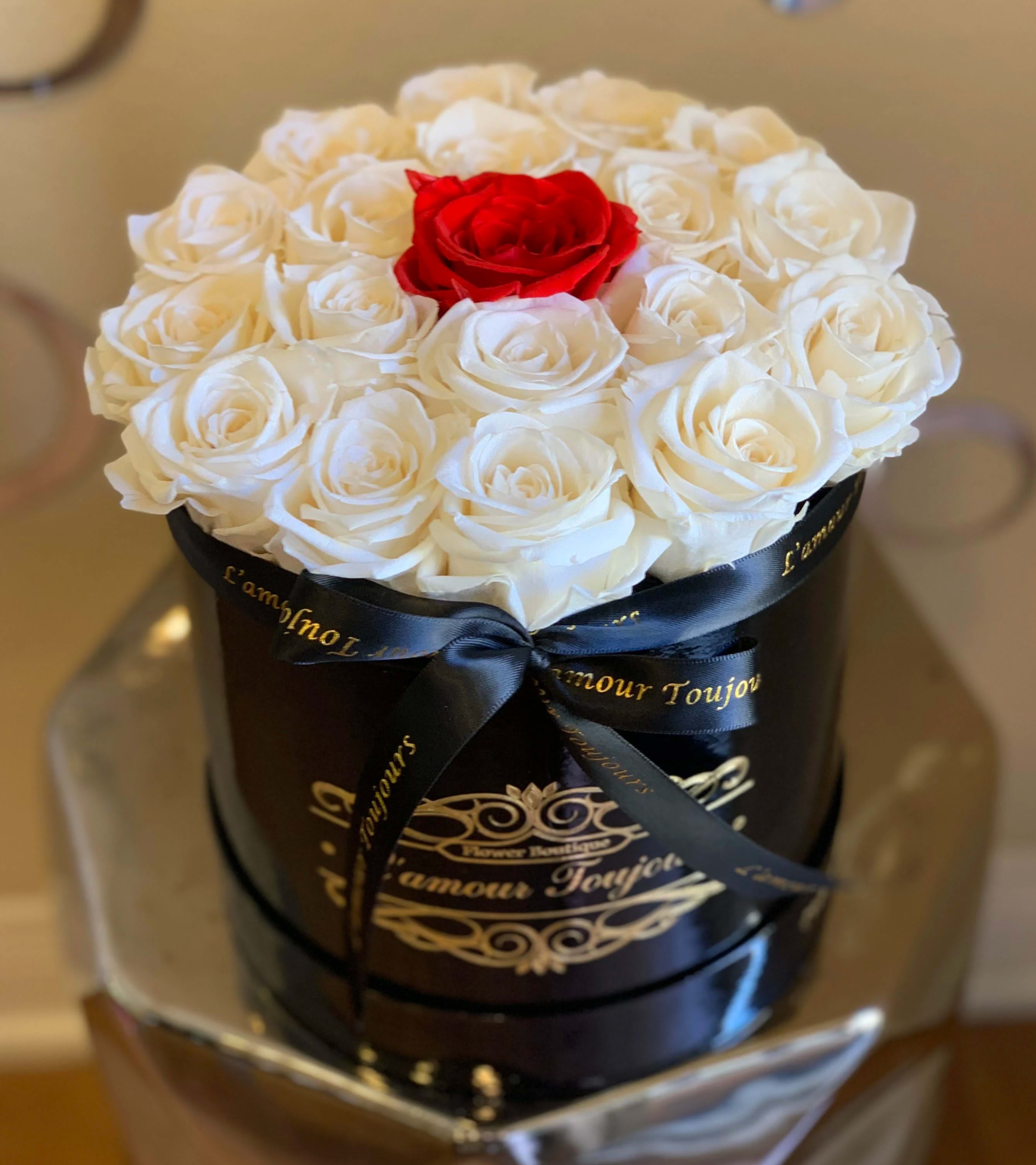 White roses with one red rose in a black round box