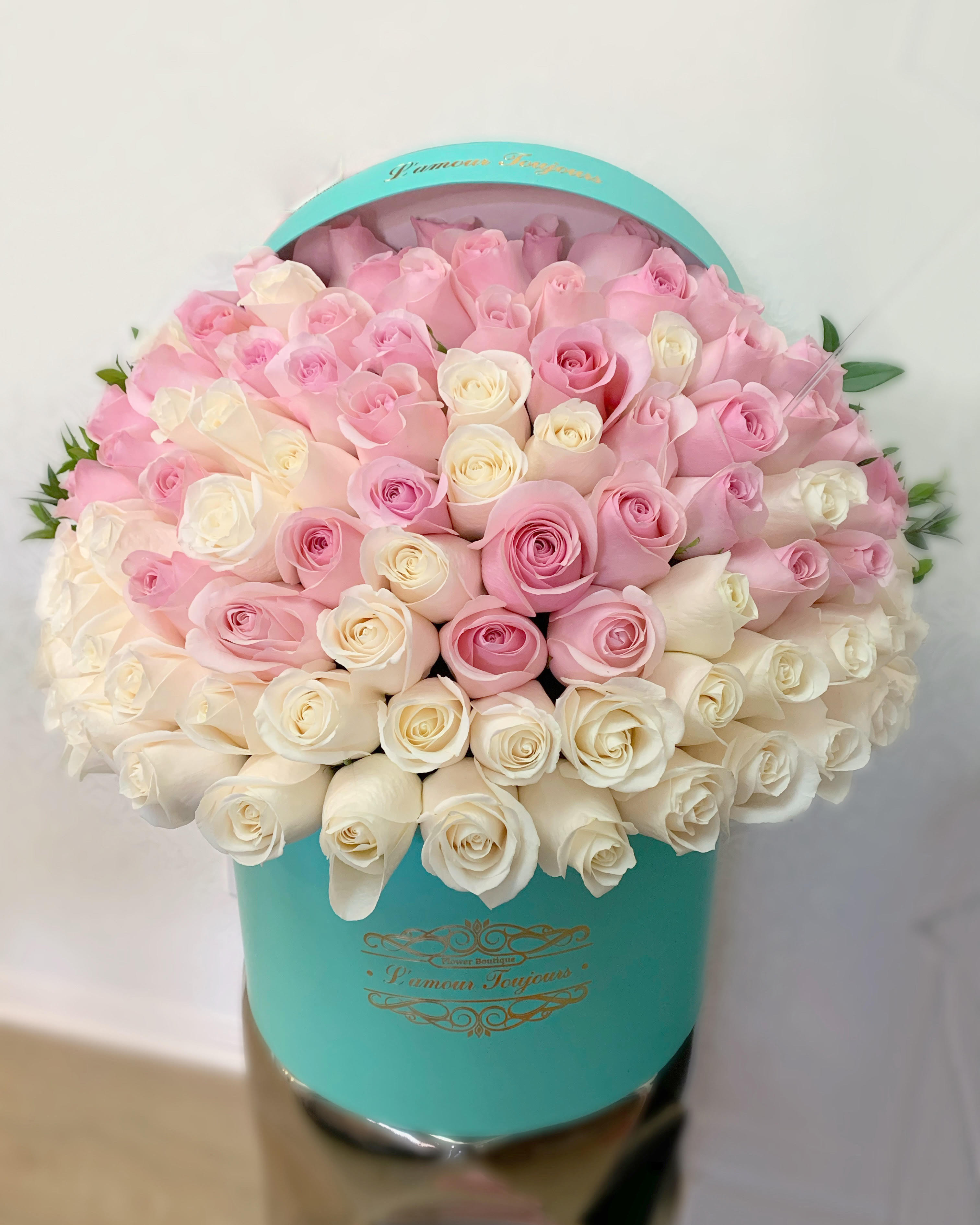 Pink and white roses arranged in a turquoise hat box
