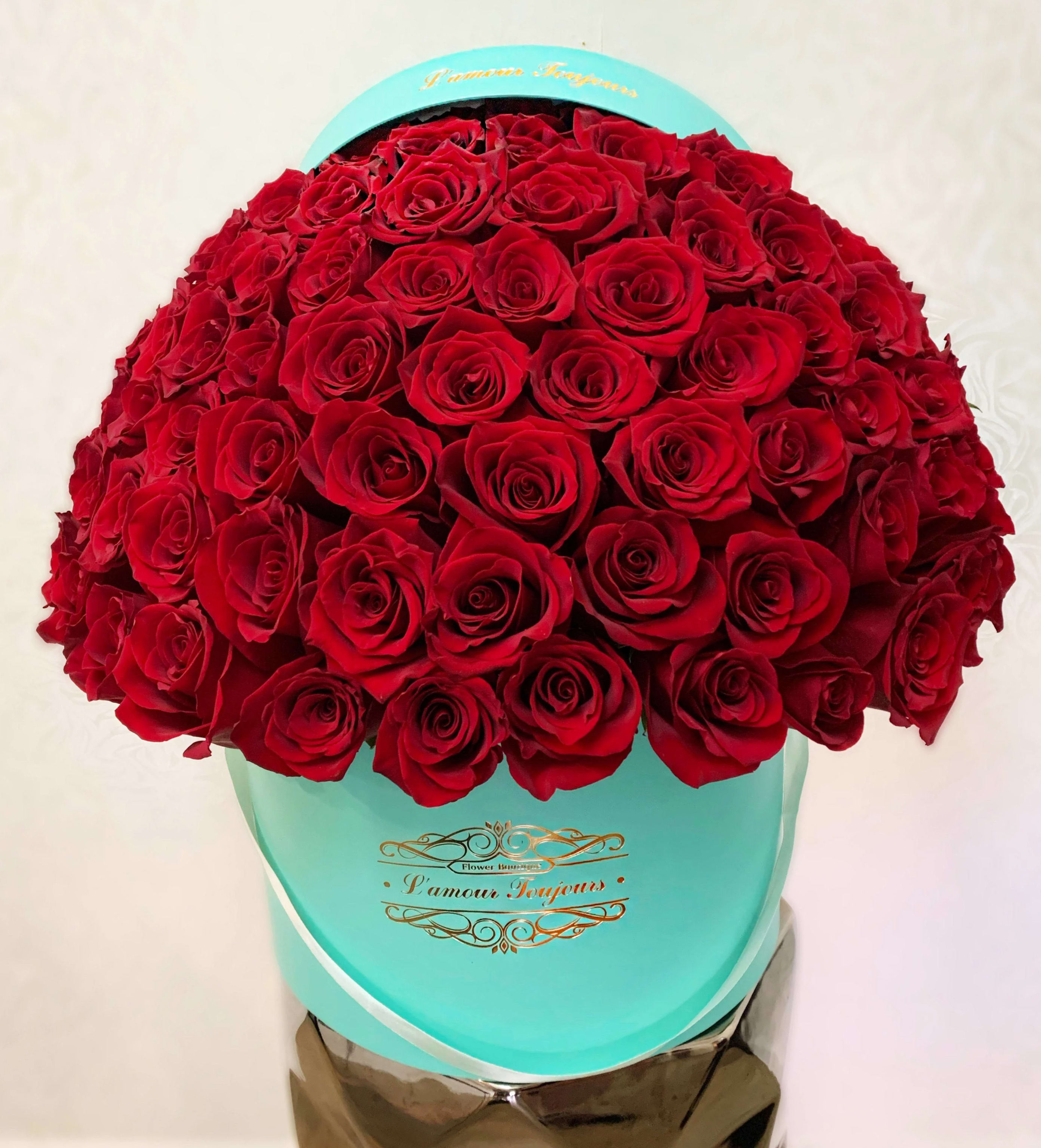 Large bouquet of red roses in a turquoise hatbox