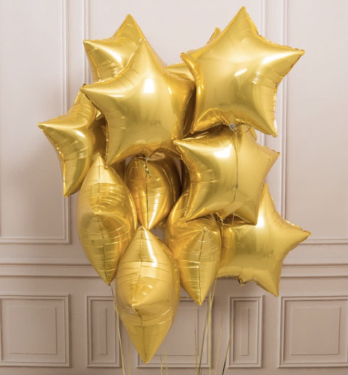 Cluster of shiny gold star-shaped balloons against a light paneled wall