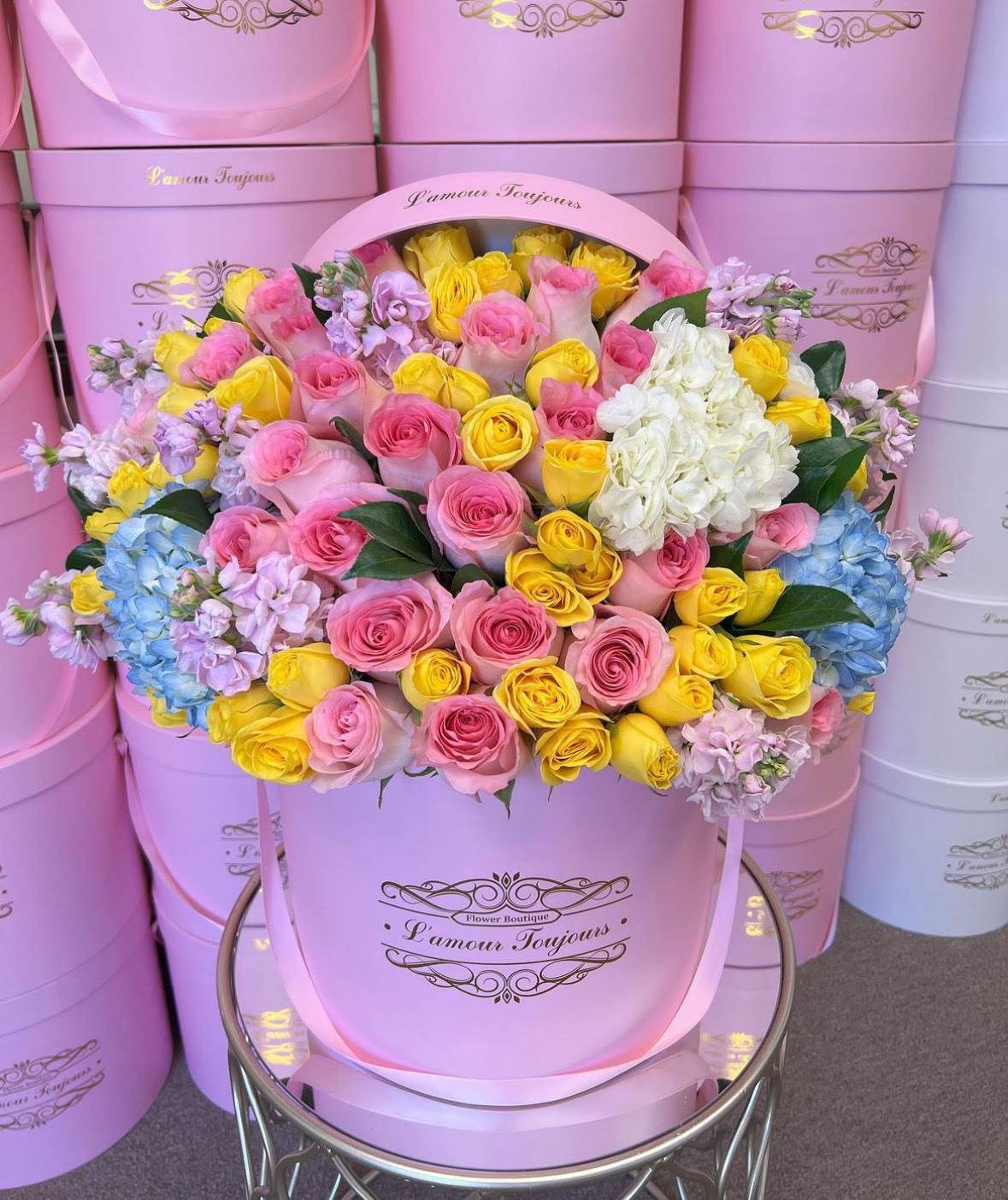 Pink hatbox arrangement of roses, hydrangeas, and lilac flowers