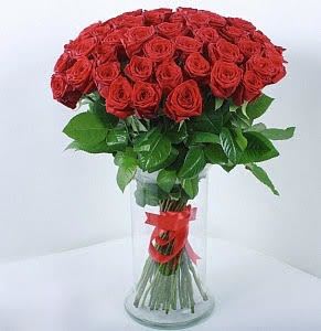 Large bouquet of red roses arranged in a tall clear glass vase with a red ribbon.
