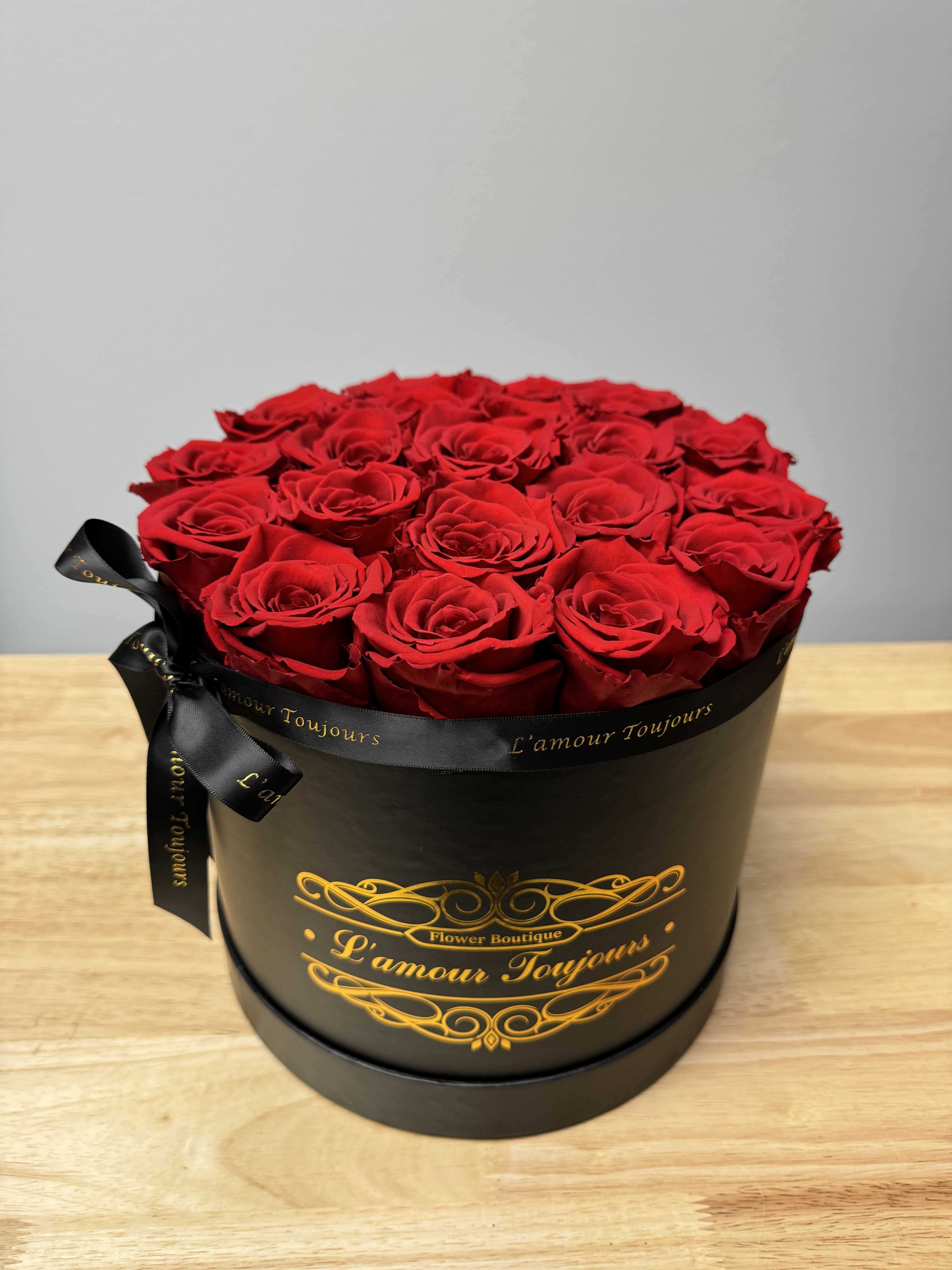 Round black hat box filled with tightly packed red roses