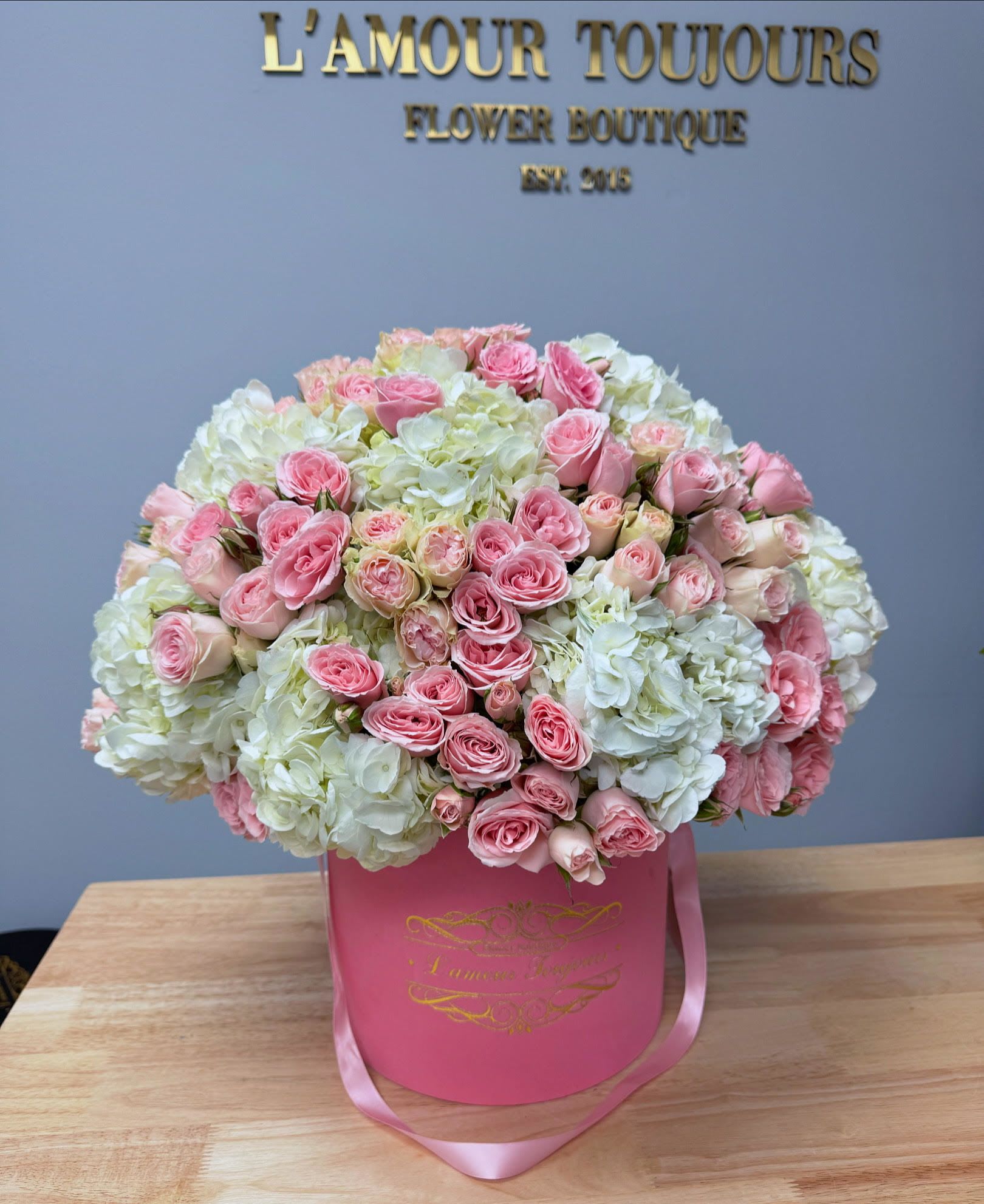 Pink roses and white hydrangeas in a pink hat box with ribbon