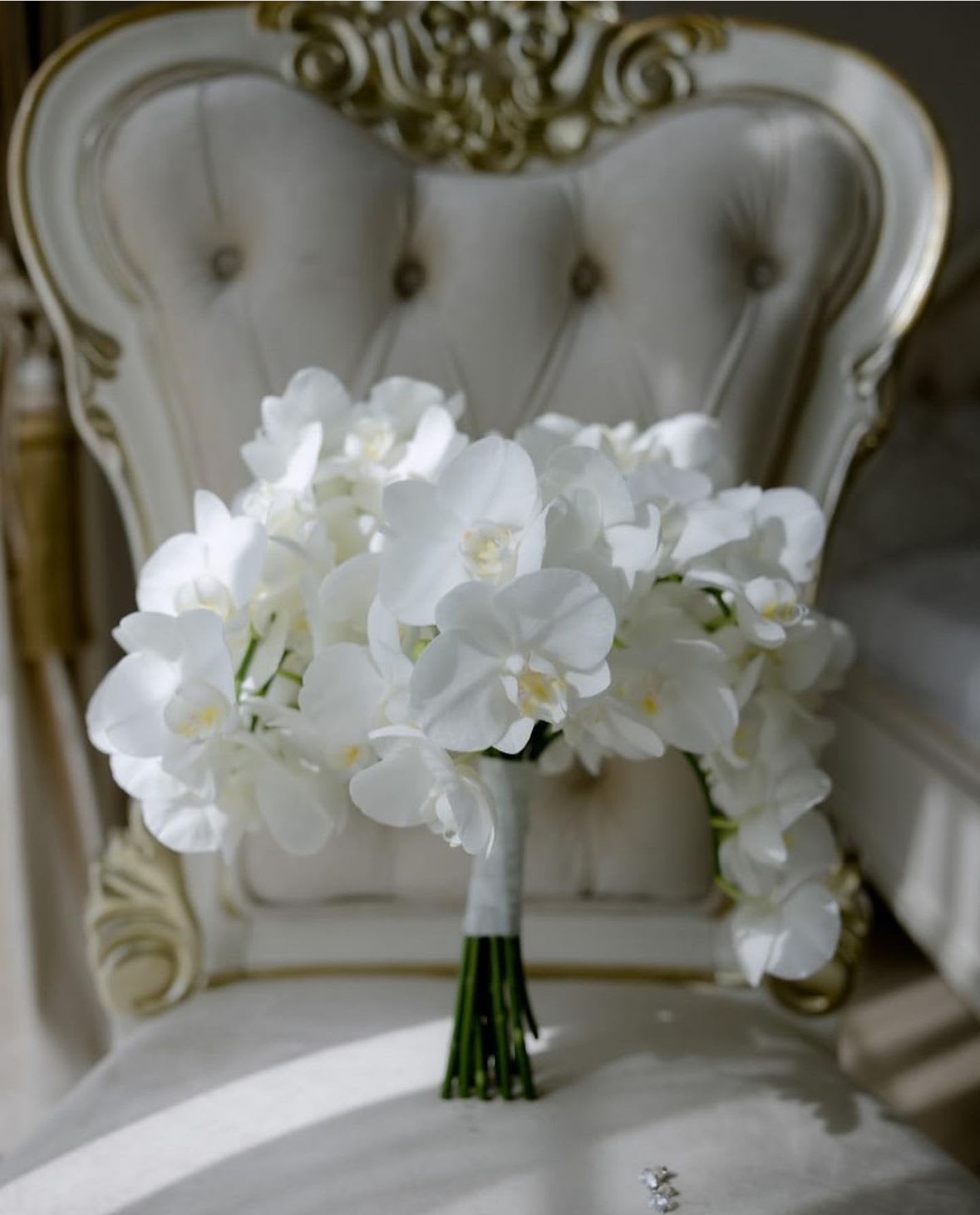 White orchid bouquet resting on an ornate chair