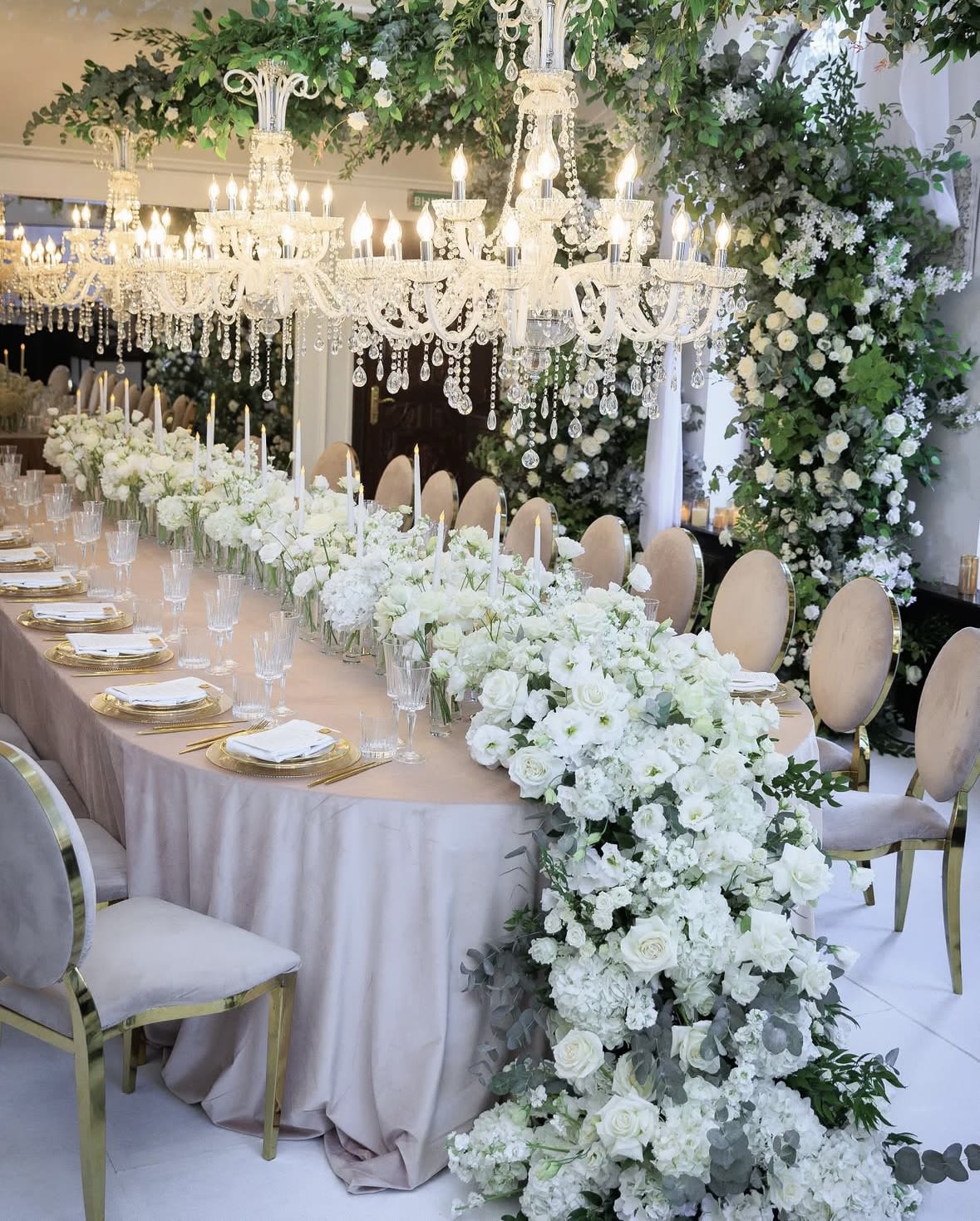 White floral wedding table with chandeliers and a long centerpiece