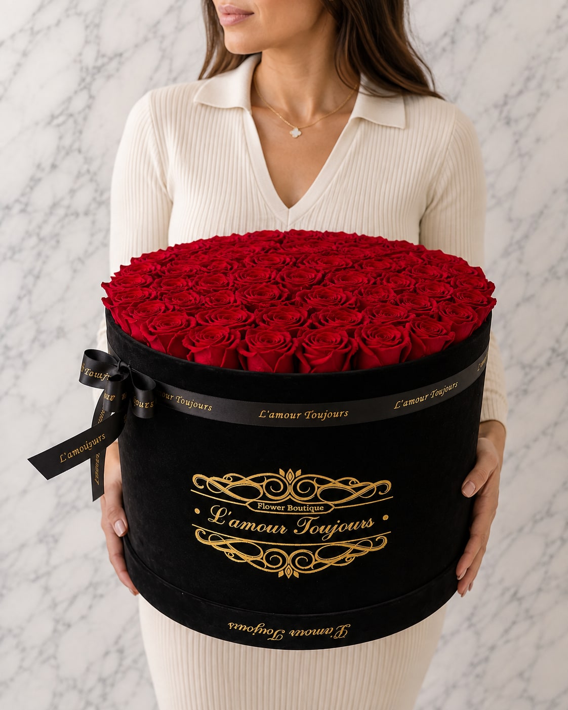 Woman holding a large round box of red roses with a black ribbon