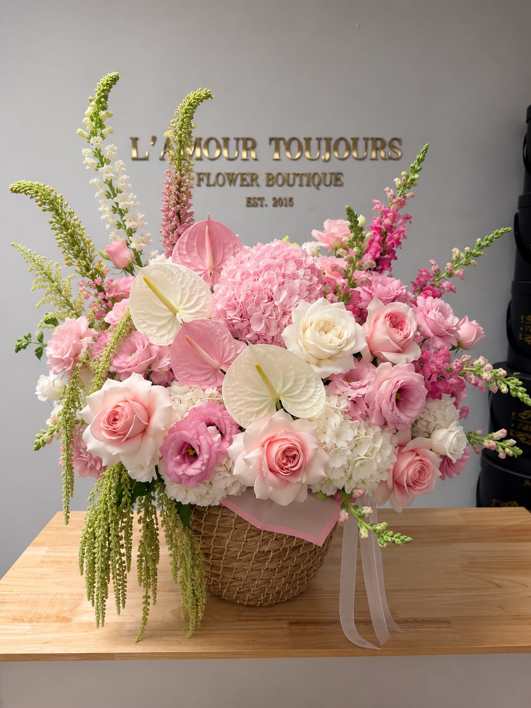 Pink and white floral arrangement in a wicker basket with ribbon