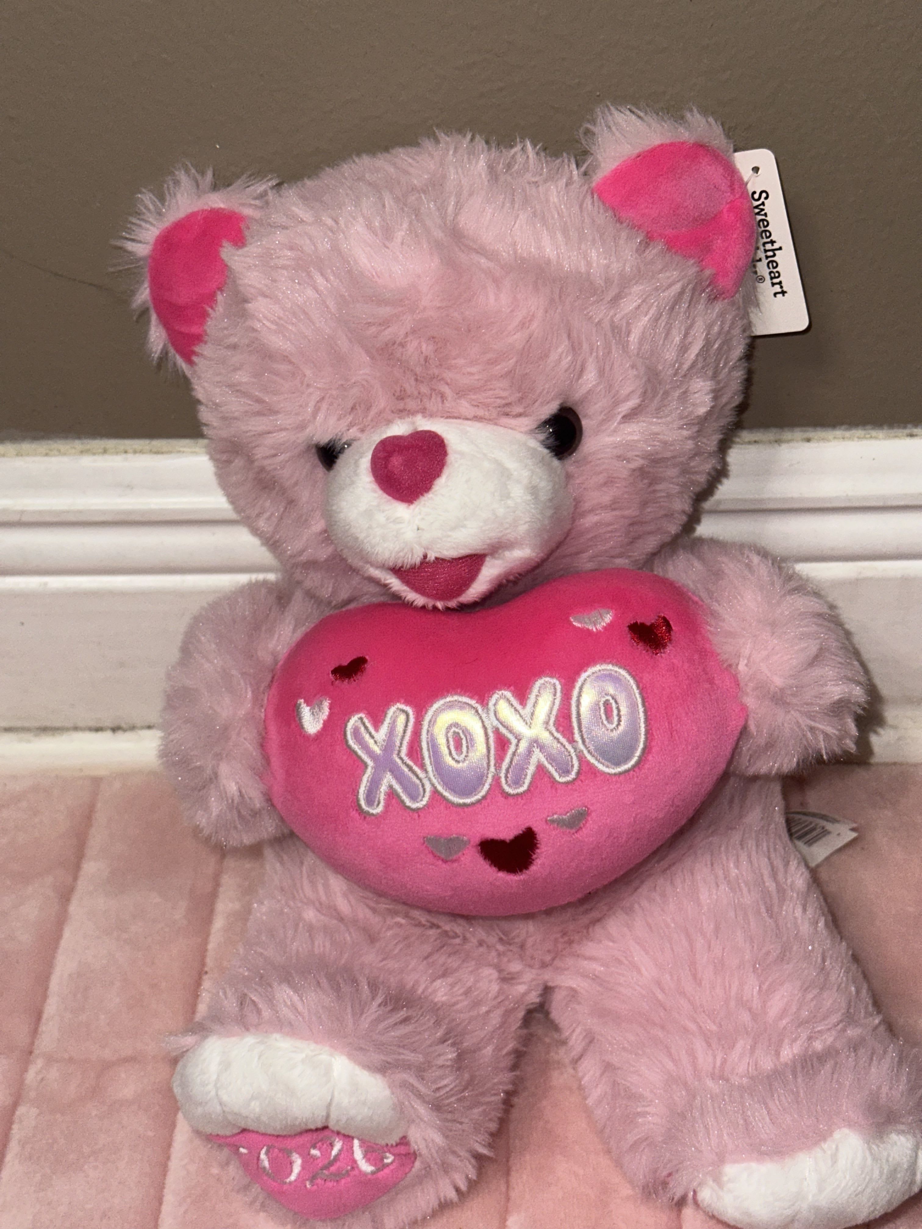 Pink teddy bear holding a heart-shaped pillow with "XOXO" text