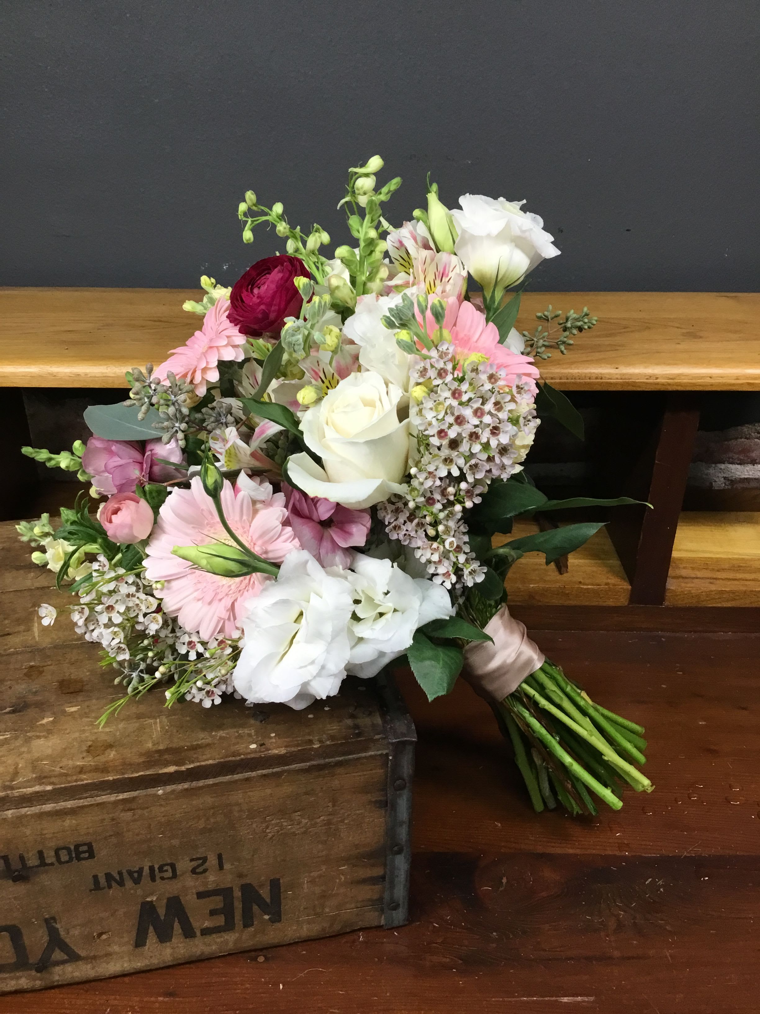 Hand-tied bouquet of pink and white flowers on a wooden surface