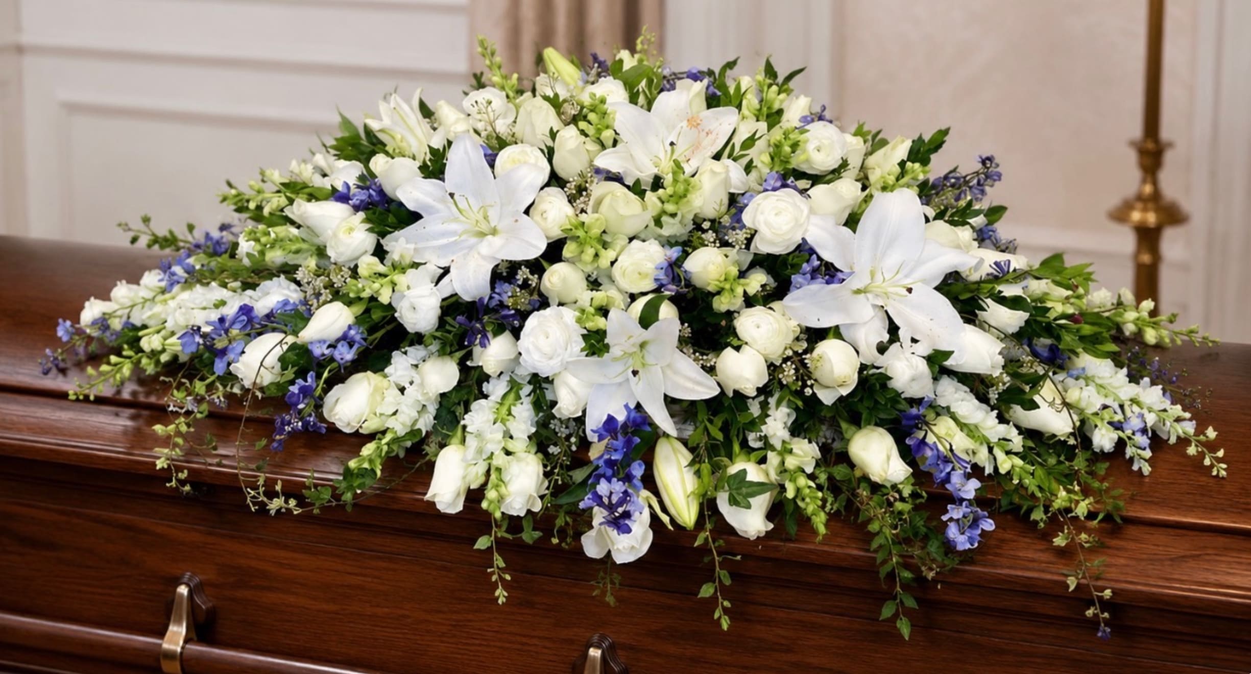 White and blue floral spray on a wooden casket