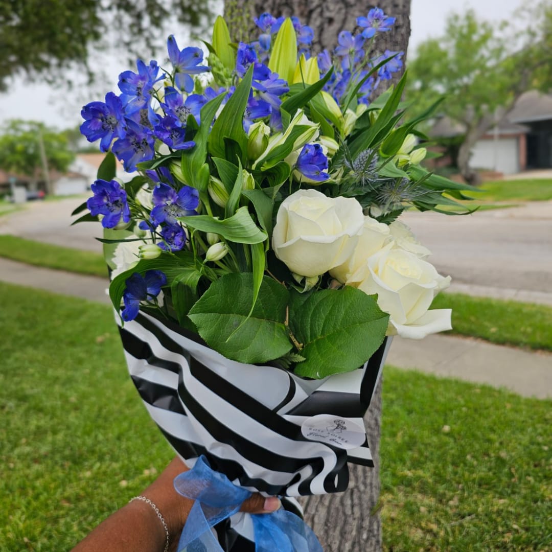 Bouquet of white roses and blue flowers wrapped in black-and-white paper