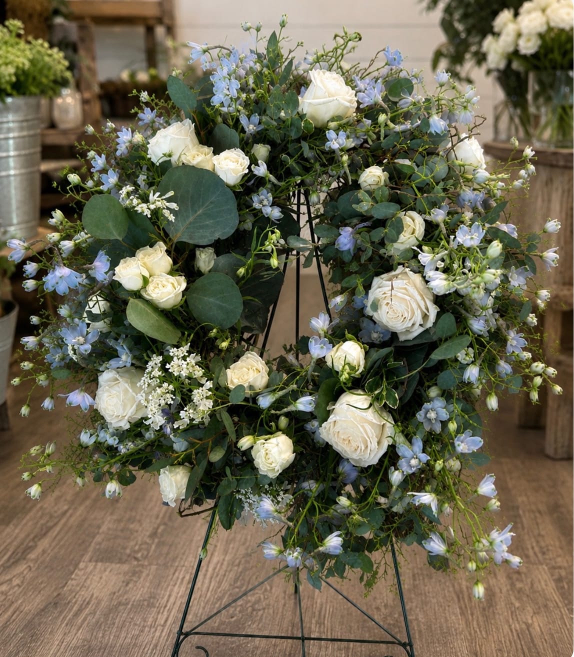 White roses and pale blue flowers arranged on a metal stand
