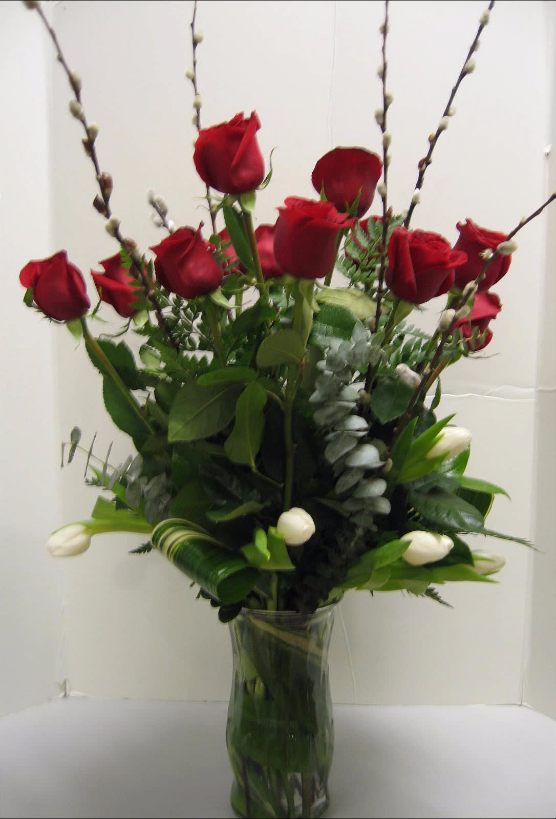 Red roses and white tulips in a clear glass vase