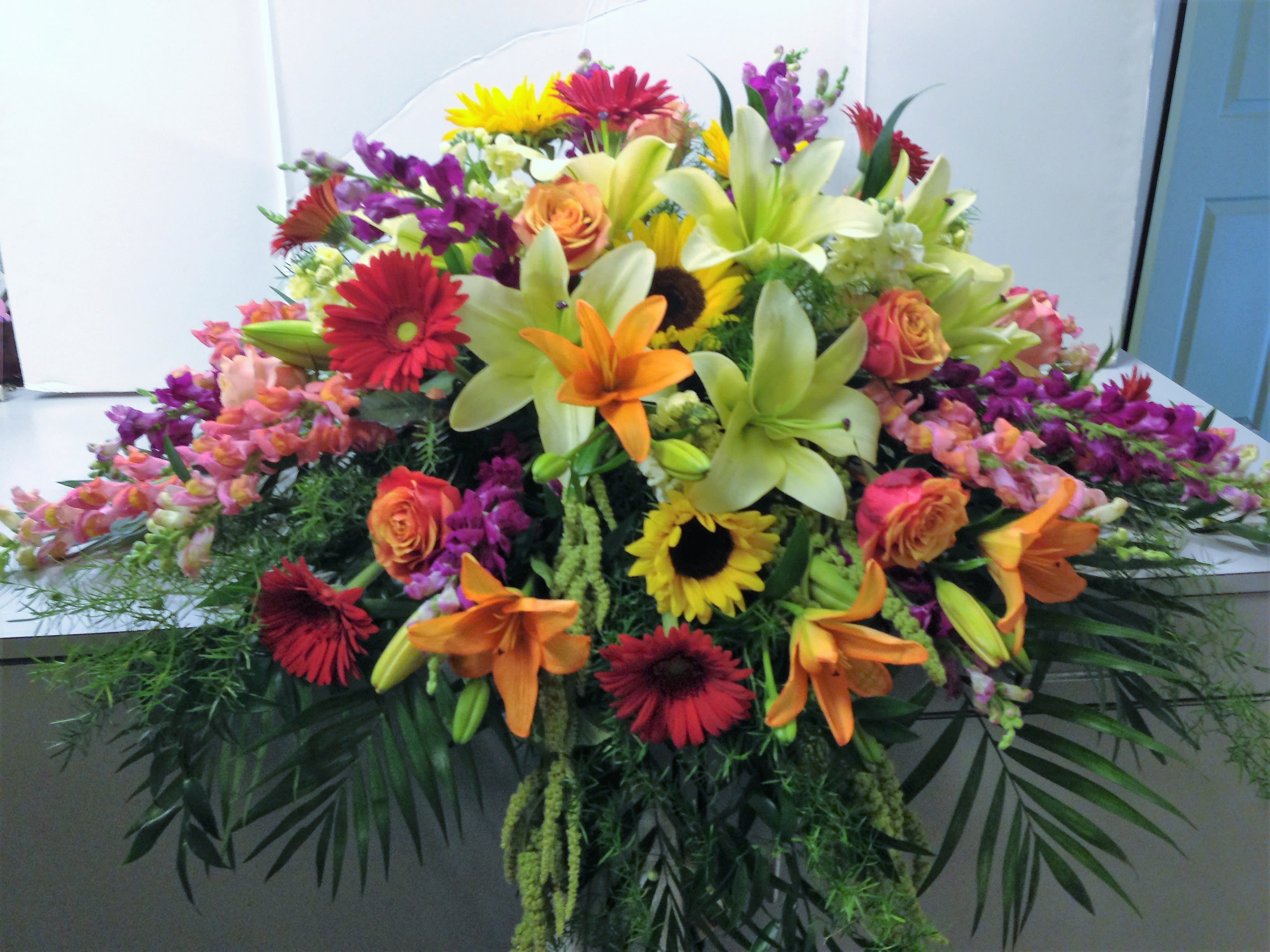 Large mixed floral spray with lilies, roses, gerbera daisies, and sunflowers