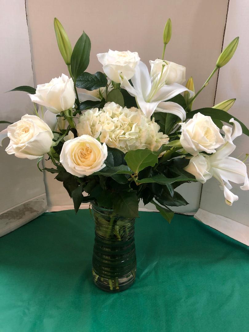 White roses and lilies arranged in a glass vase
