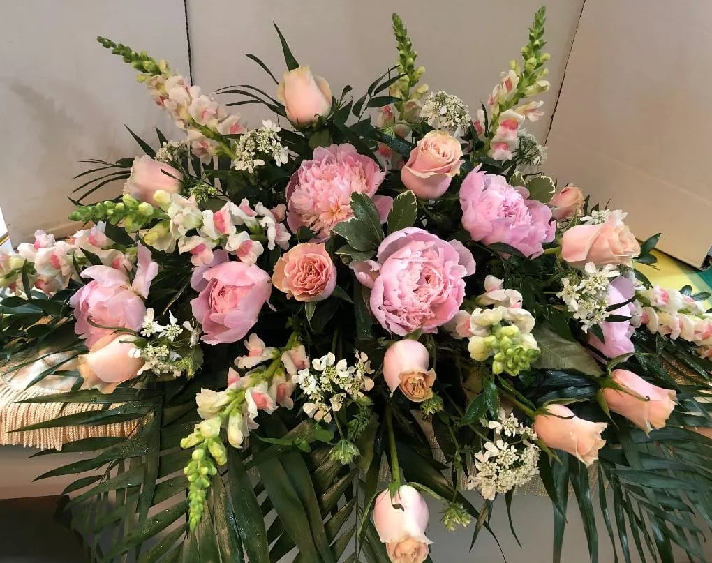 Pink roses and peonies arranged with snapdragons and greenery
