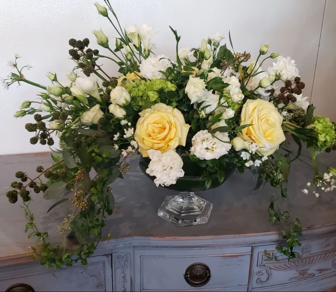 Cream and white floral arrangement in a clear pedestal vase