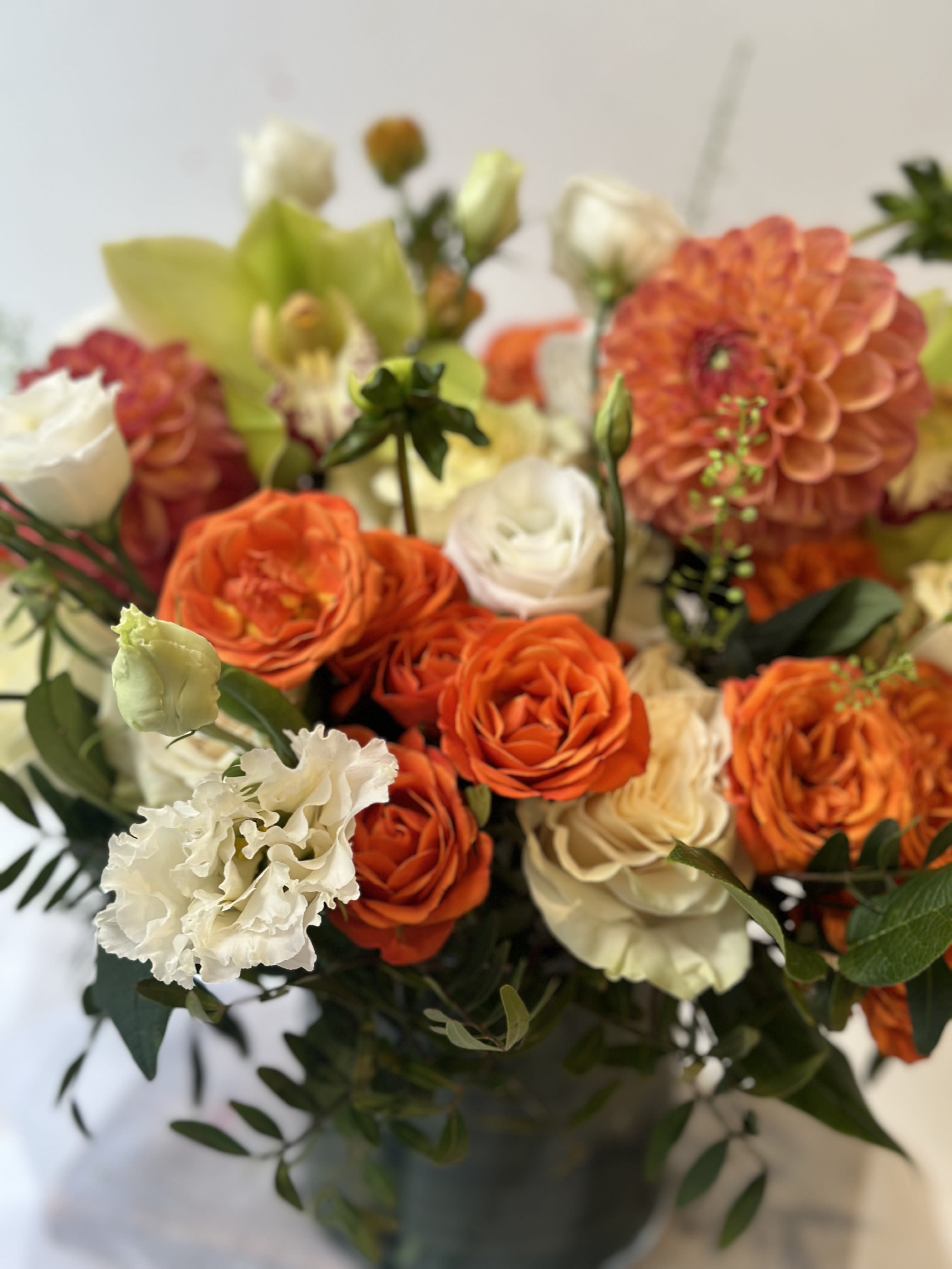 Orange and white roses with a peach dahlia in a vase