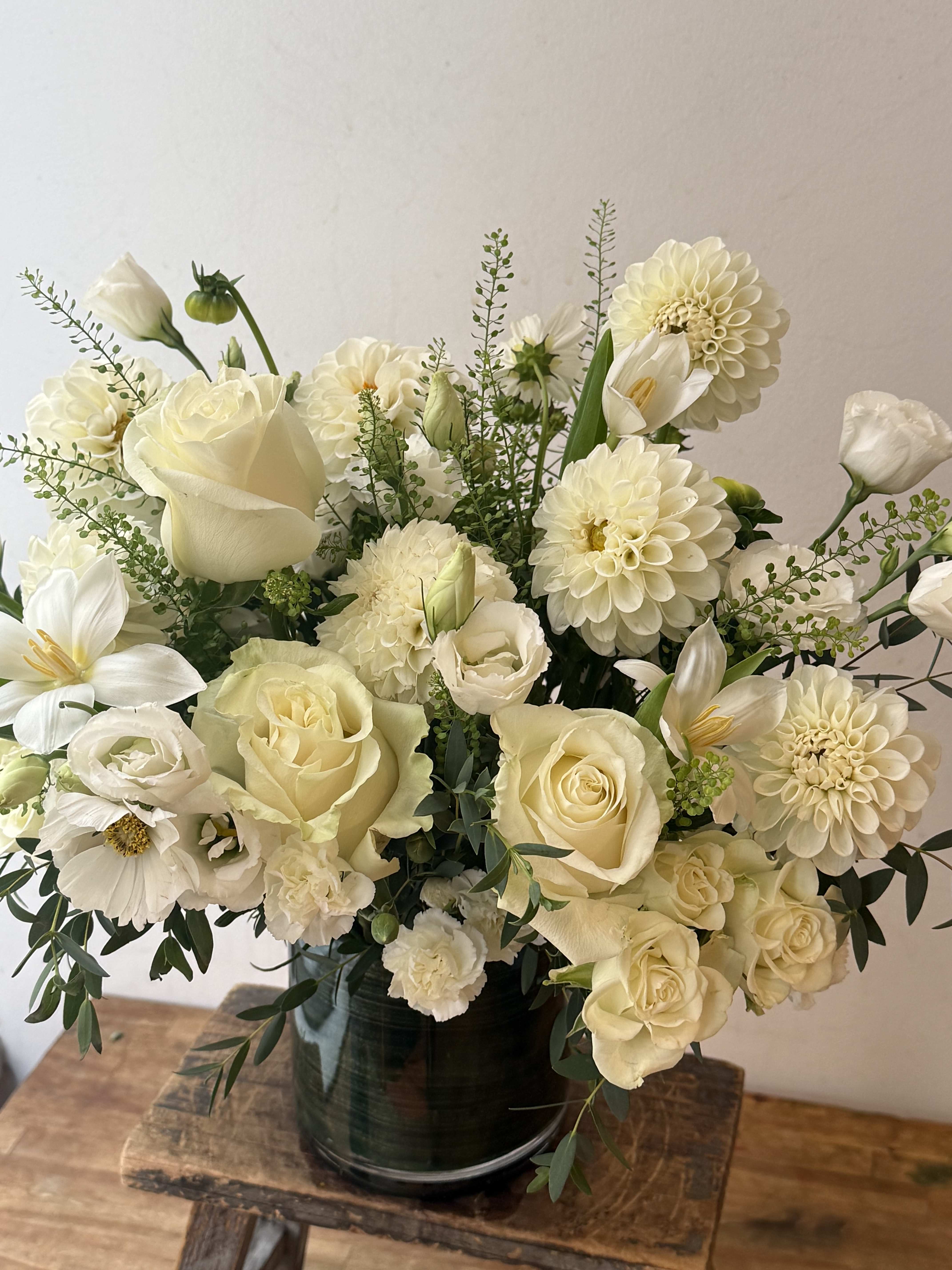 Creamy white bouquet of roses, dahlias, and calla lilies in a dark vase