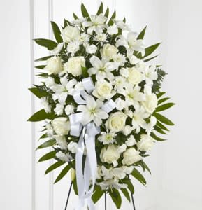 White funeral spray with lilies and roses on a stand