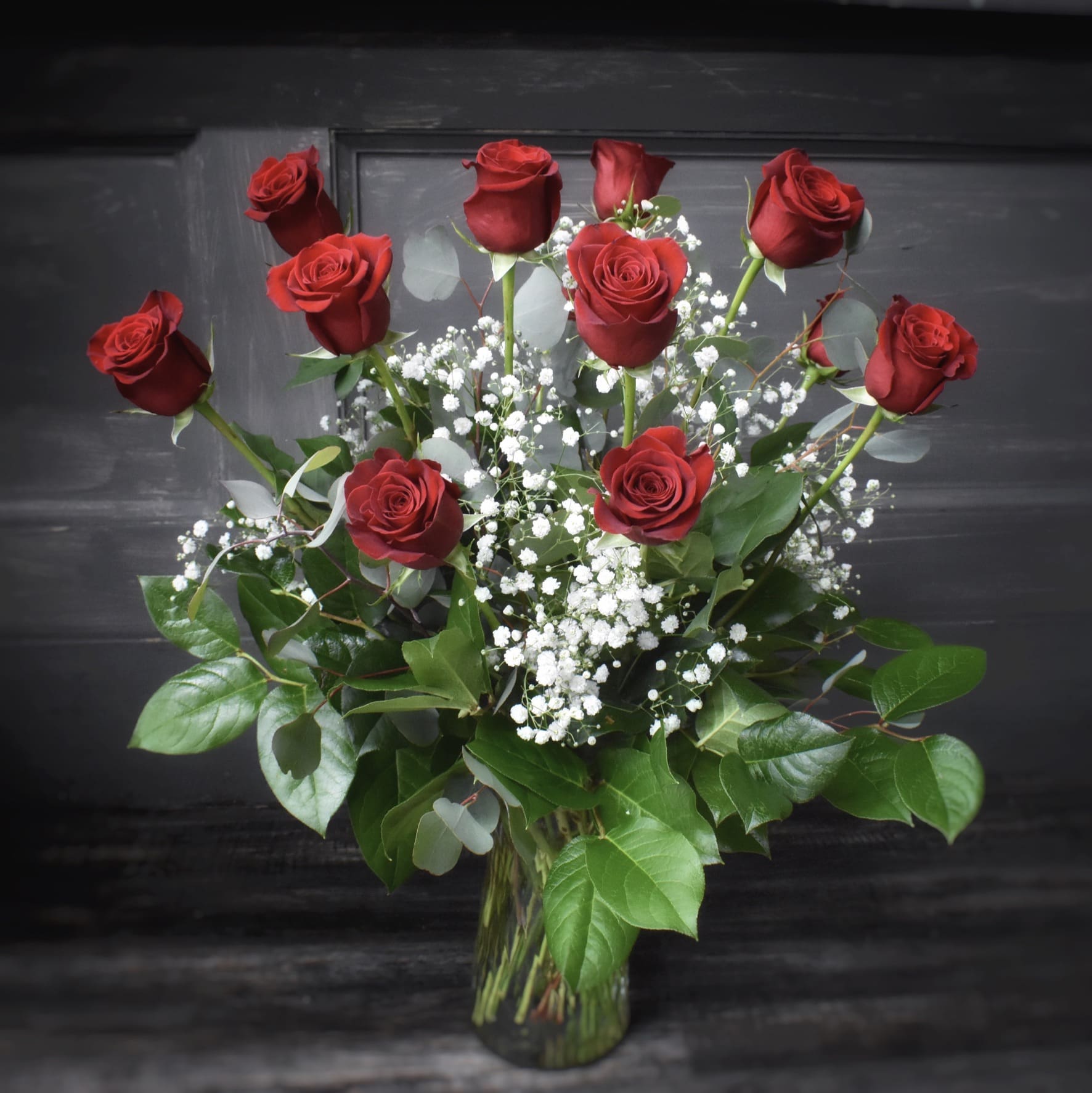 Enduring Love - One dozen Long stemmed red roses artfully designed in a glass vase with an assortment of greens and babies breath.  Approx. 20"h x  20"   