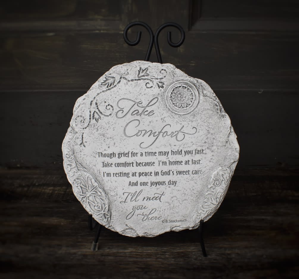 Round decorative plaque on a black stand with the words "Take Comfort"