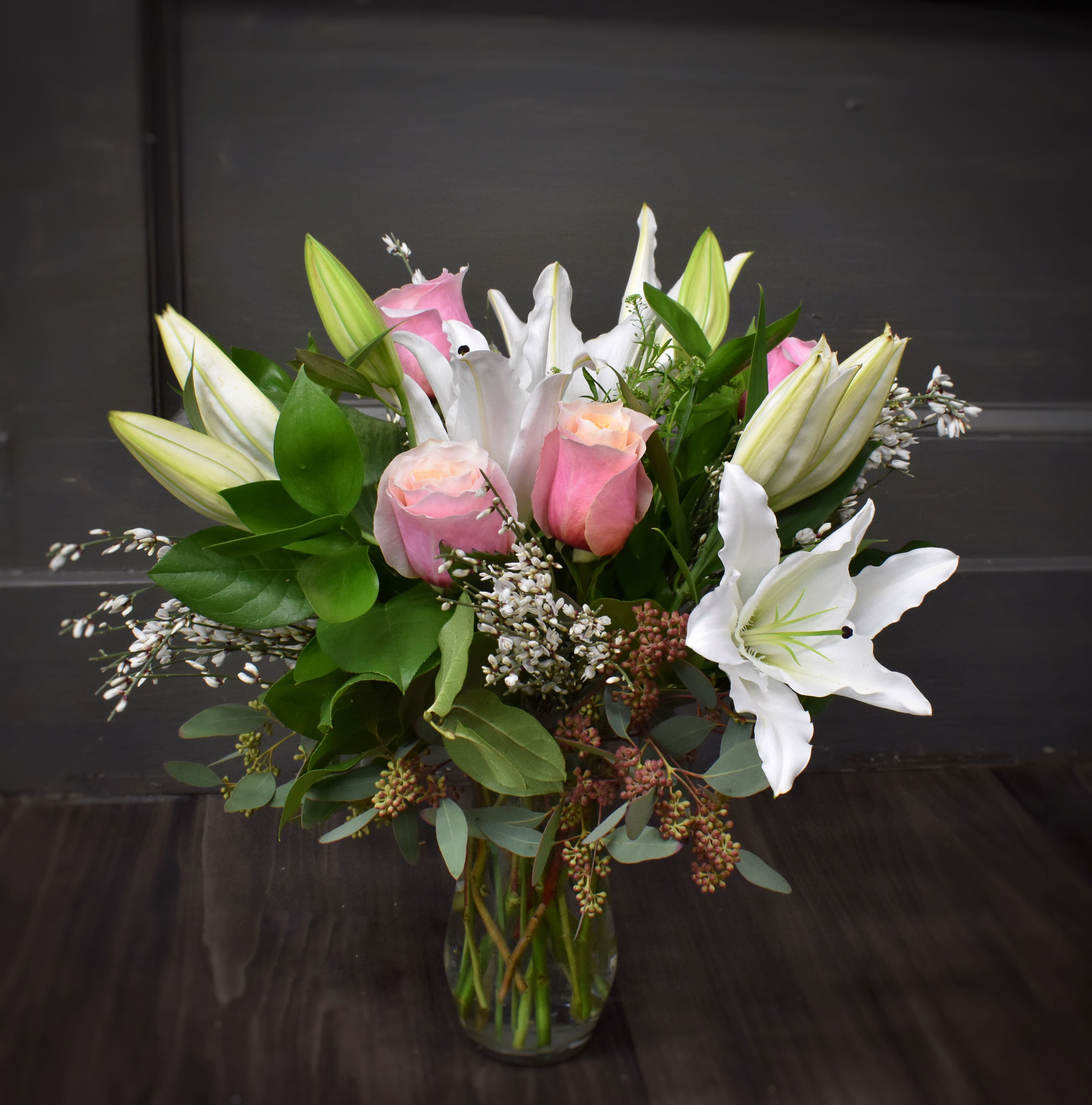 Pink roses and white lilies arranged in a clear glass vase