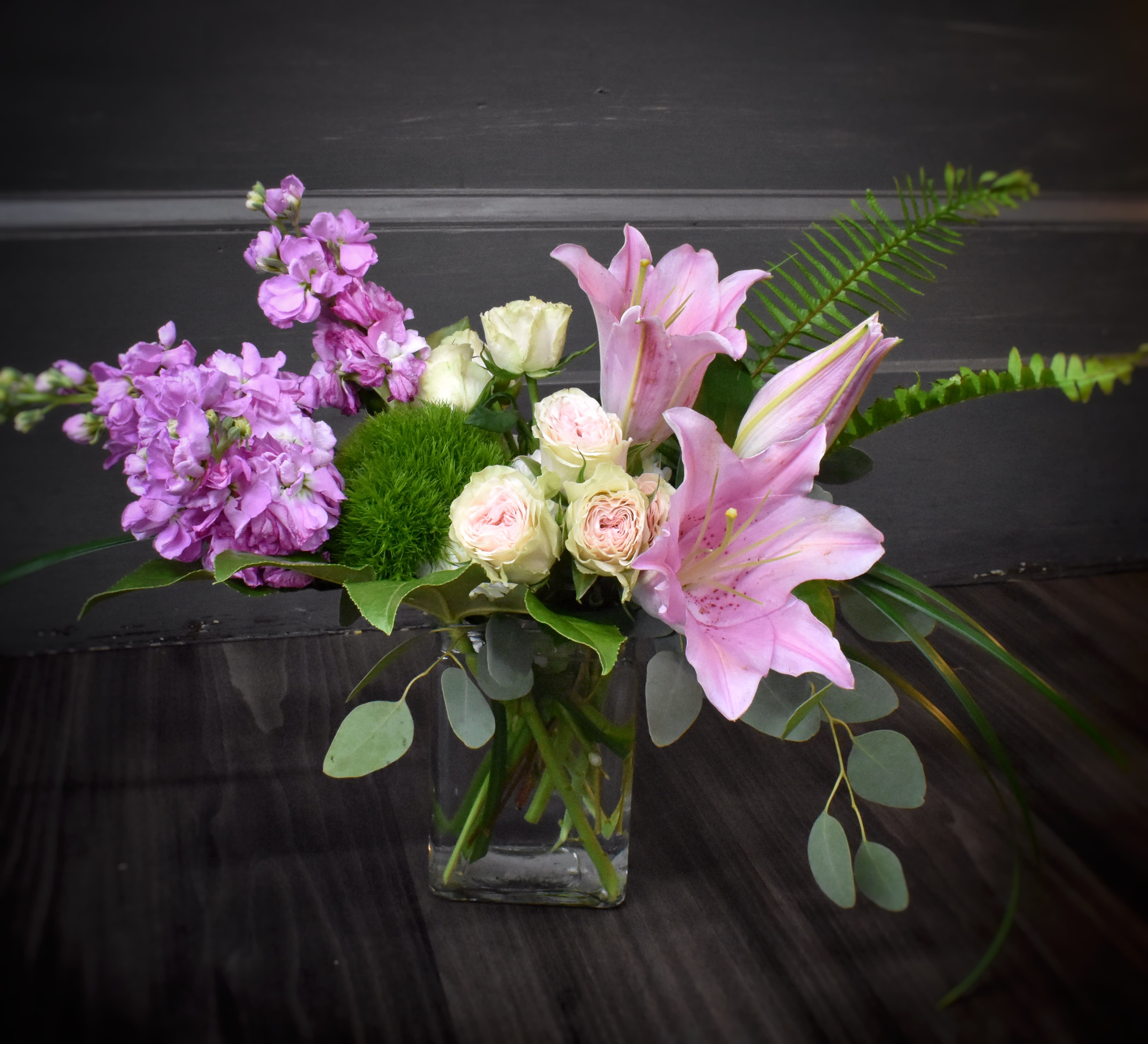 Pink lilies and lavender flowers in a glass vase