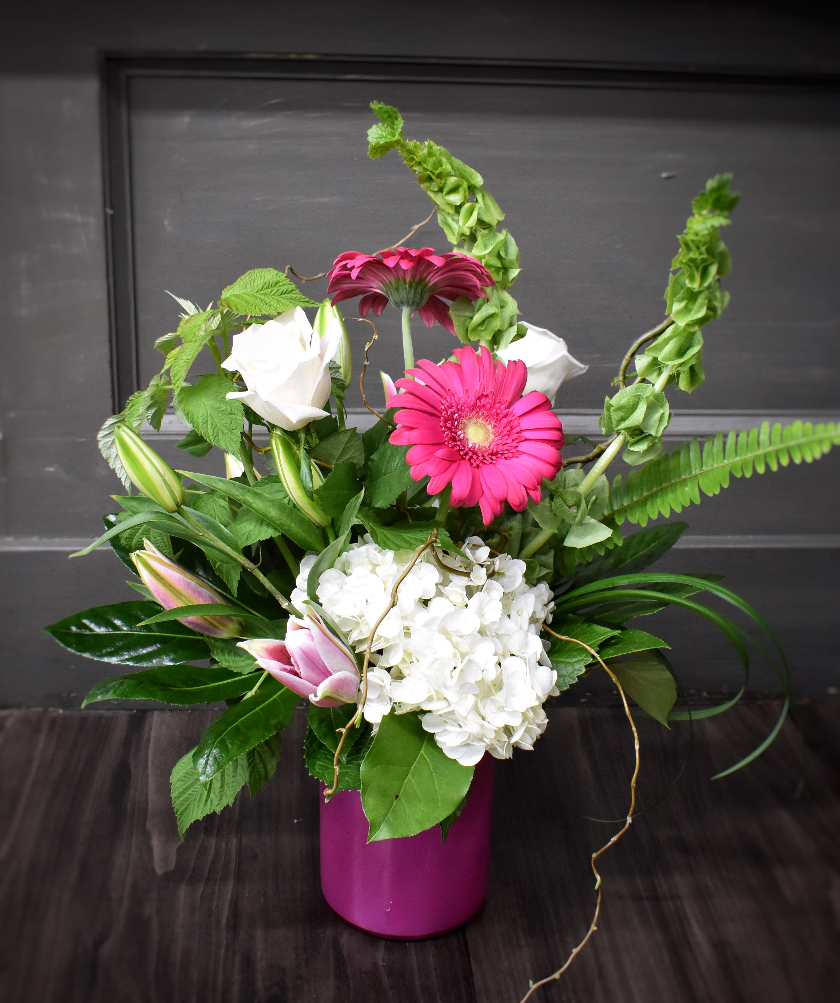 Pink gerbera daisies and white roses in a magenta vase