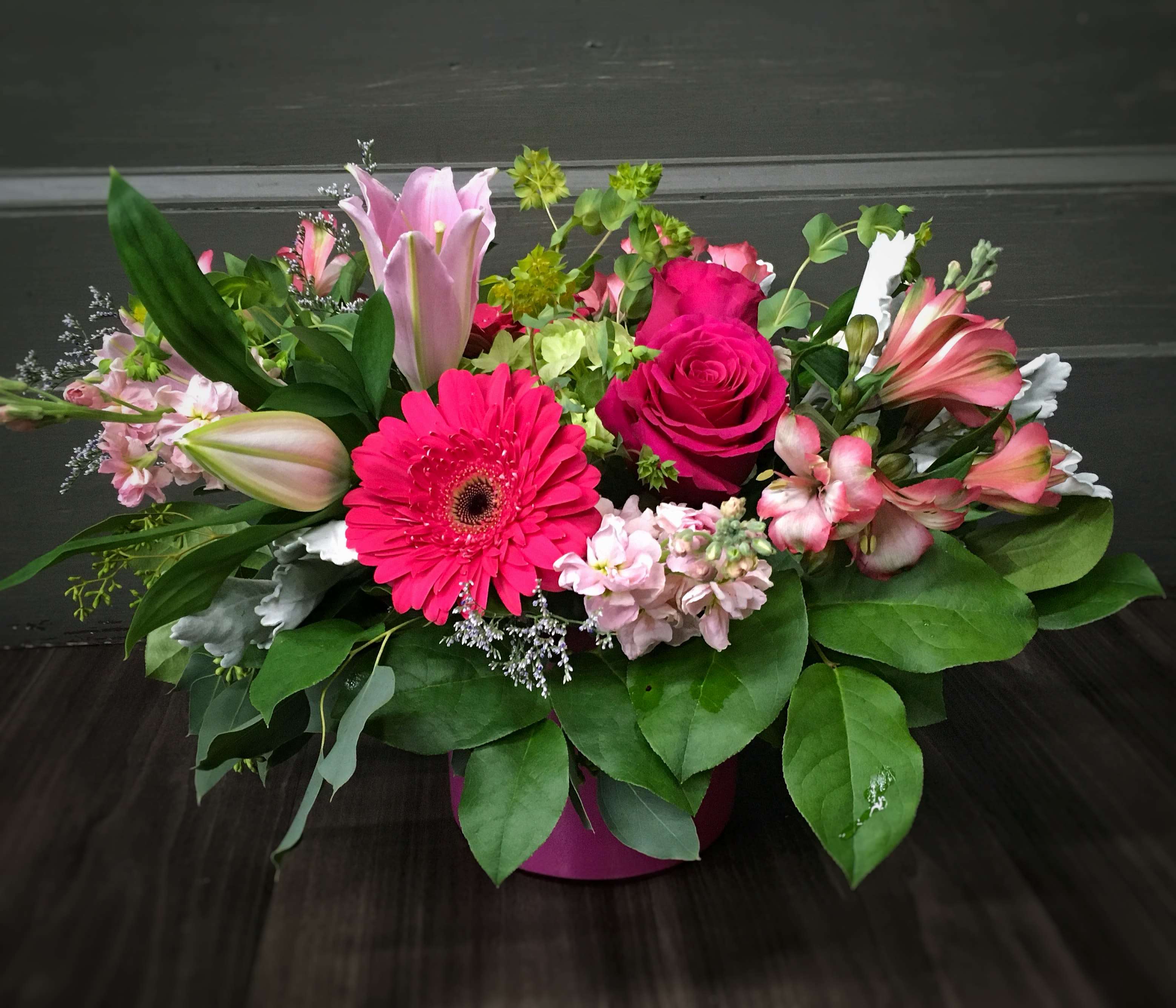 Mixed pink floral arrangement in a round pink container