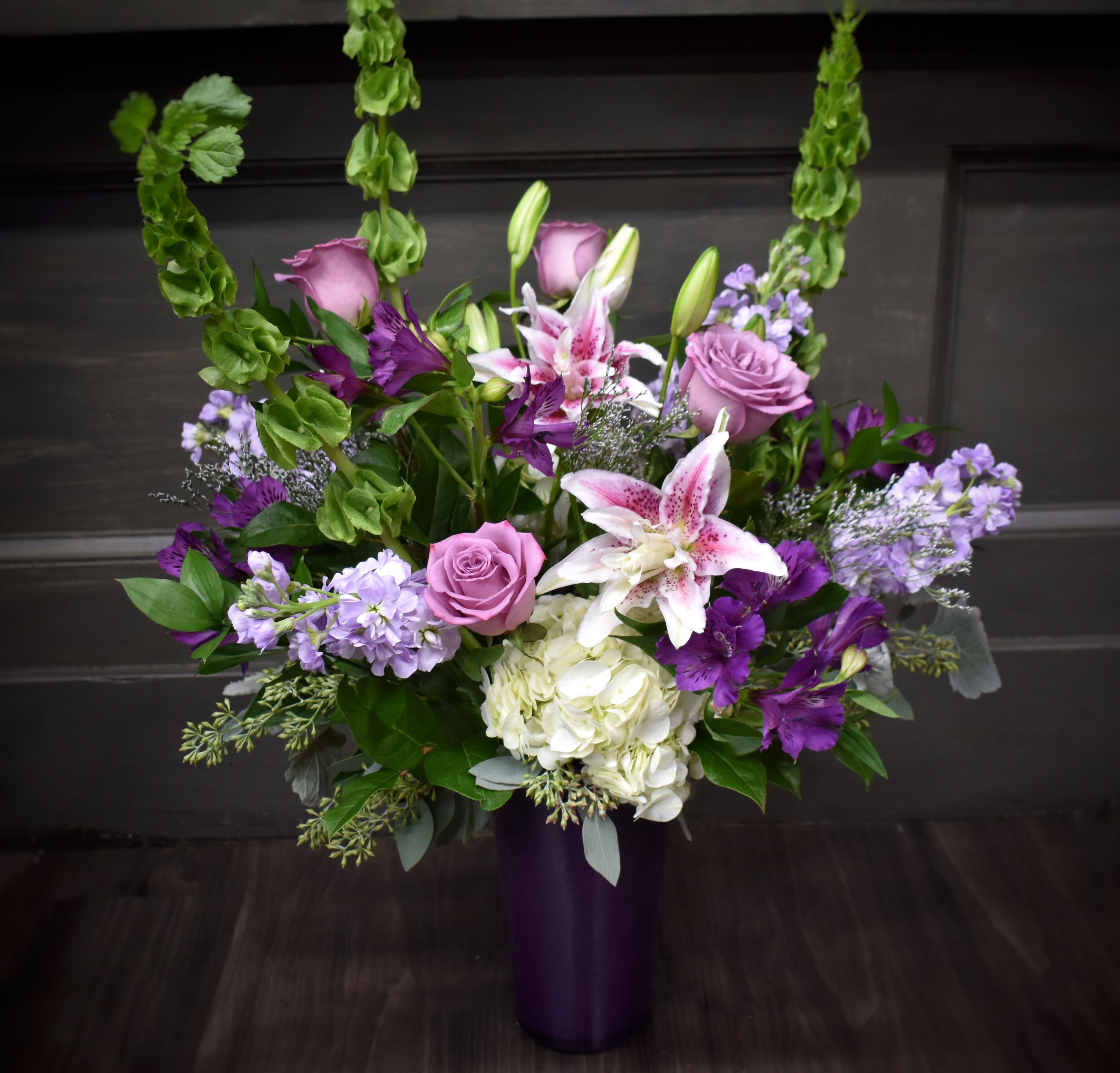 Purple and white floral arrangement in a tall vase