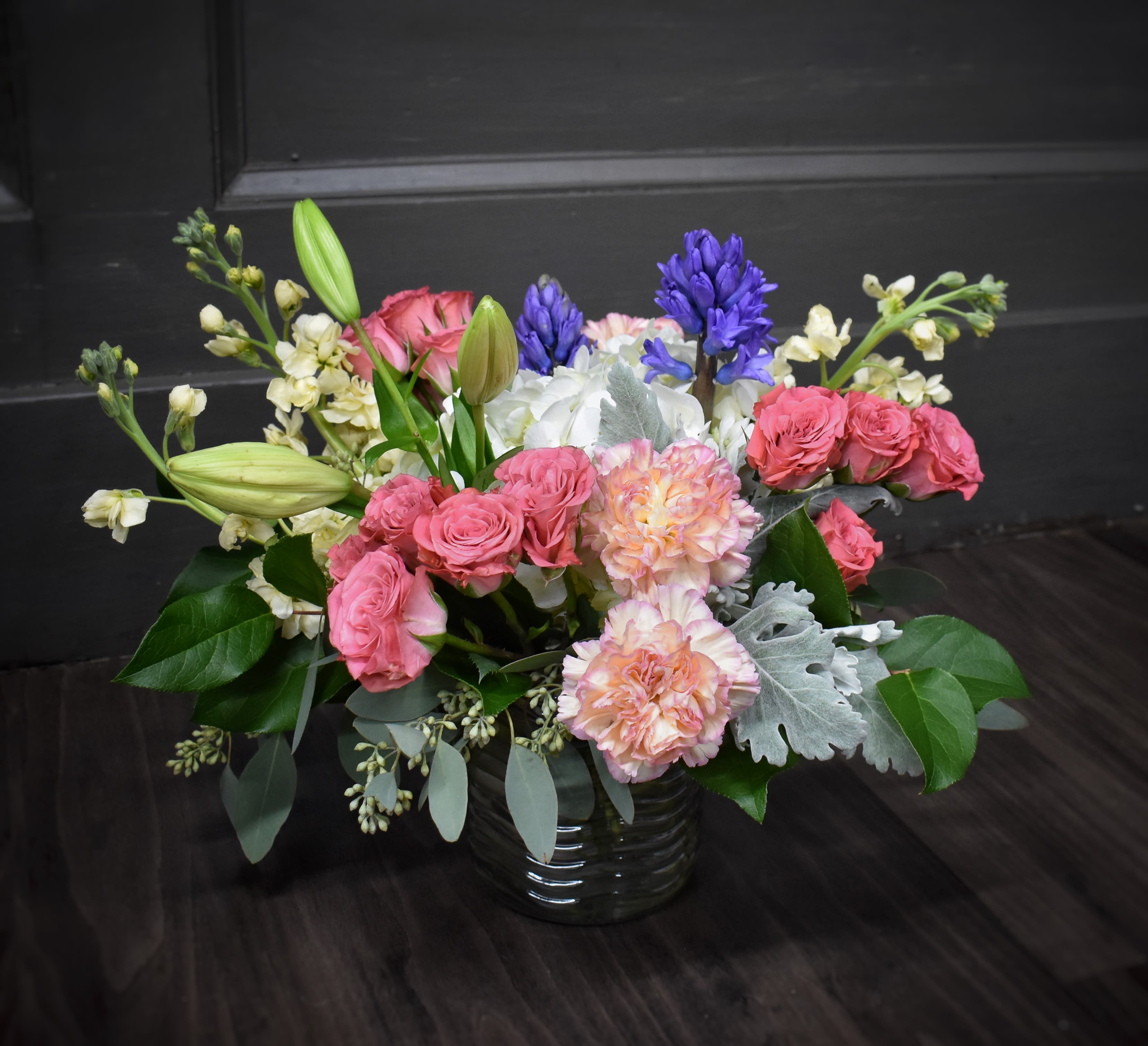 Pink roses and peach carnations in a glass vase with purple hyacinths