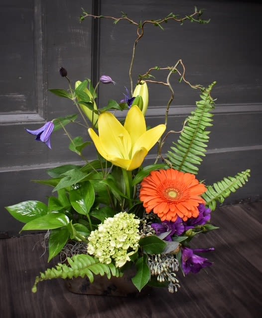 Mixed floral arrangement with yellow lilies and an orange gerbera daisy
