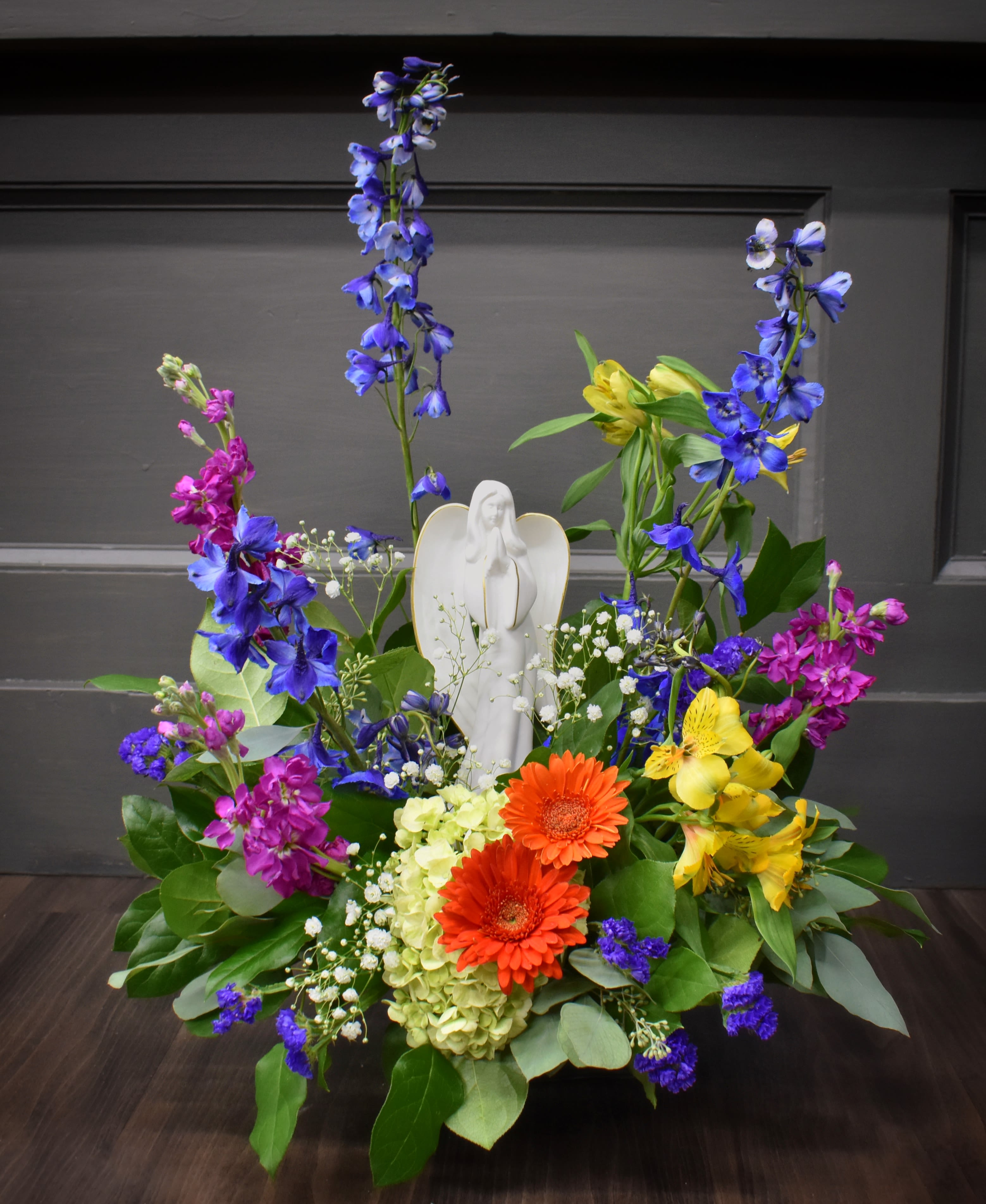 Colorful floral arrangement with an angel figurine in the center