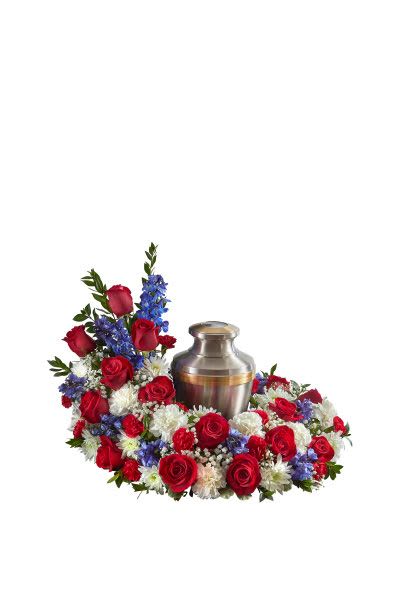 Cremation urn surrounded by red, white, and blue flowers in a circular sympathy arrangement
