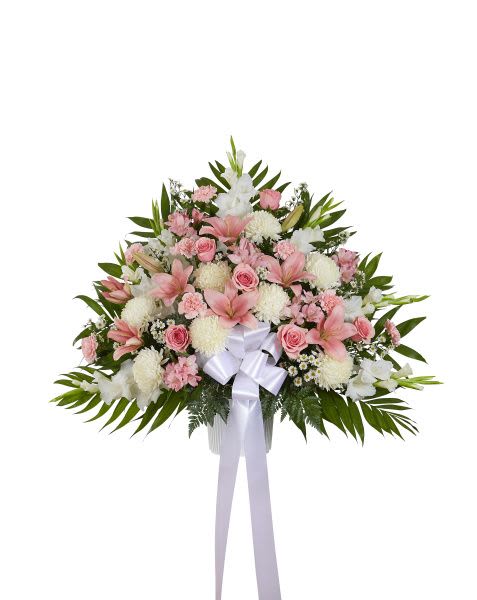Fan-shaped standing arrangement of pink lilies, roses, and white mums with a white bow.