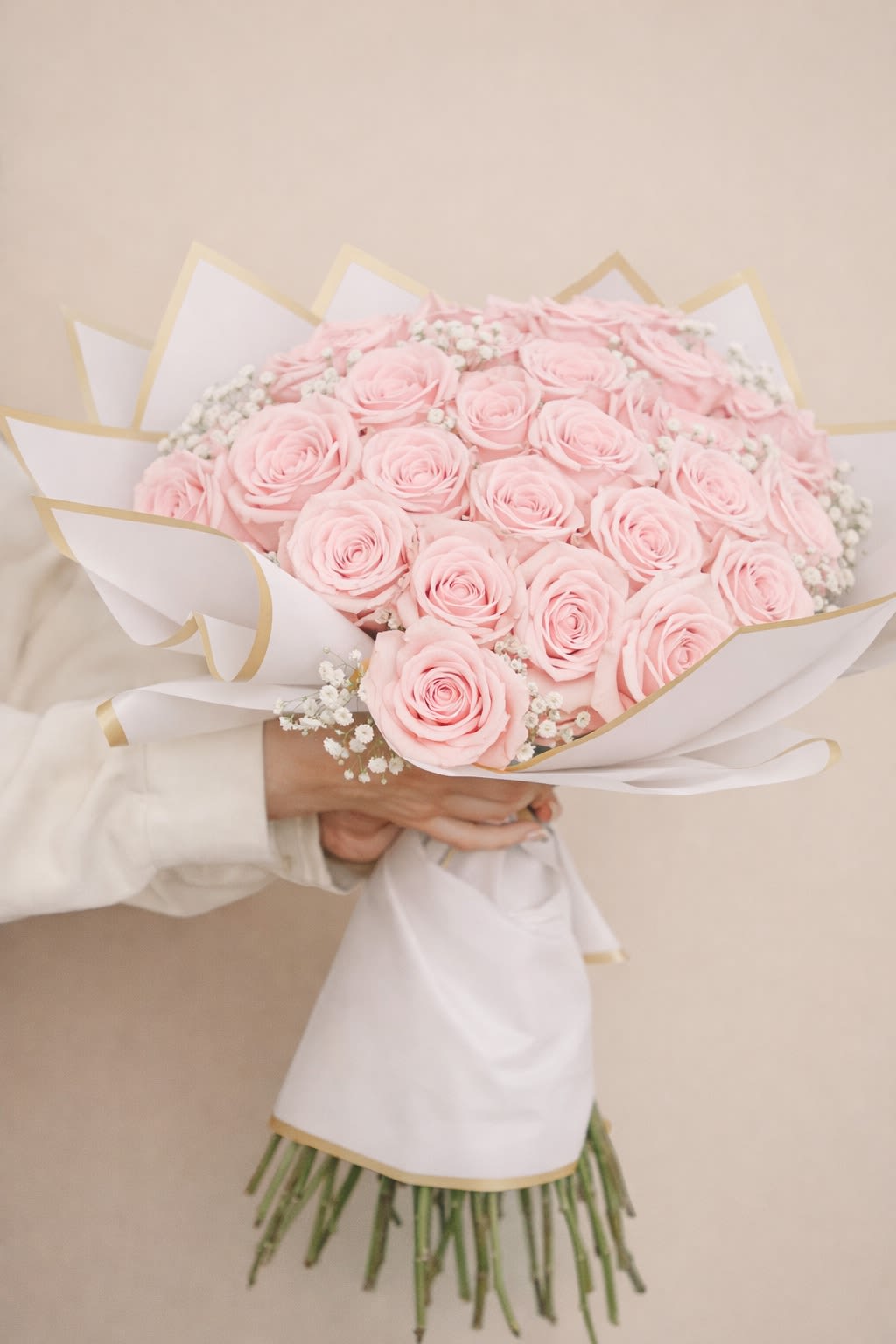 Bouquet of pale pink roses wrapped in white paper with gold trim