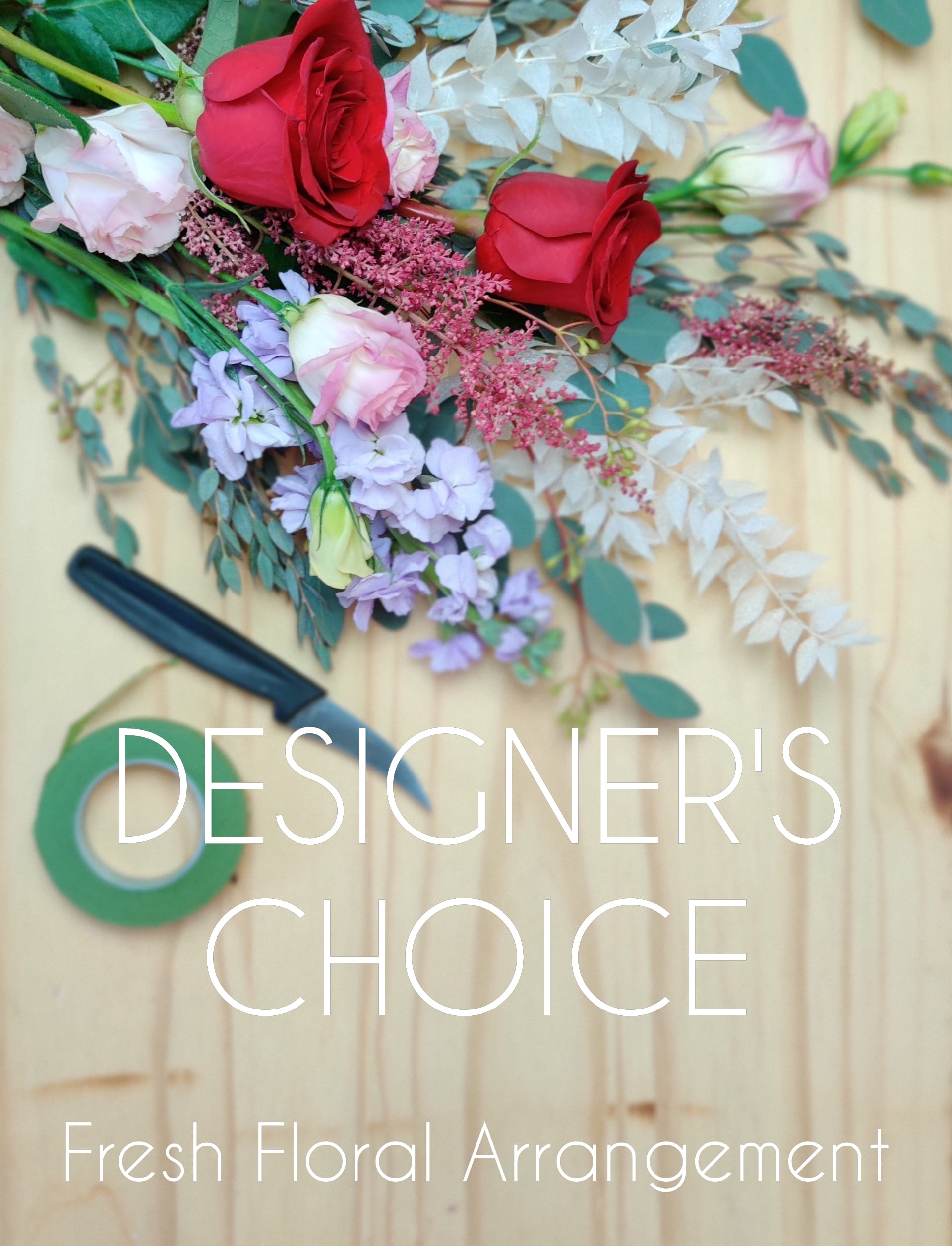 Assorted roses and pastel flowers with greenery on a wooden surface