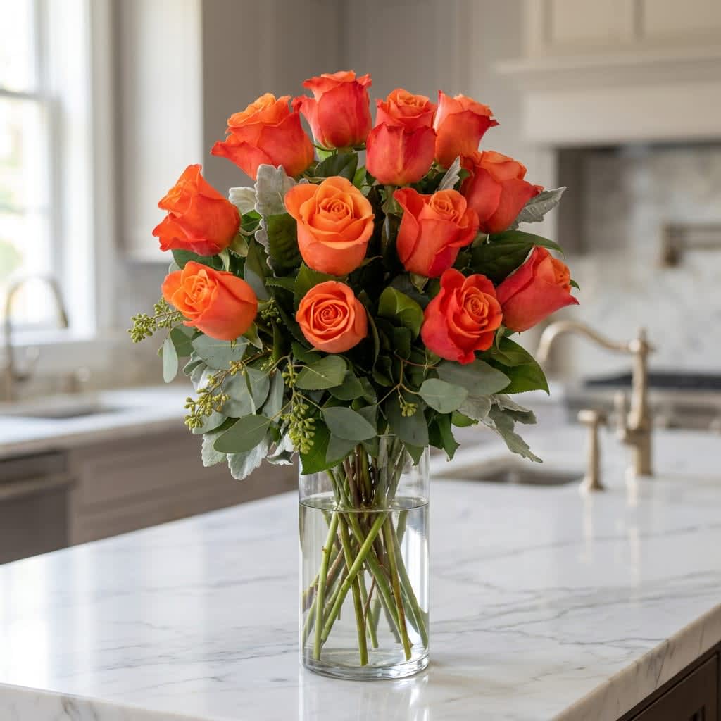 Dozen Orange Roses - Embrace the vibrant allure of one dozen long stem orange Ecuadorian roses beautifully arranged in an 11" clear glass vase, accompanied by delicate fillers and lush greens. 