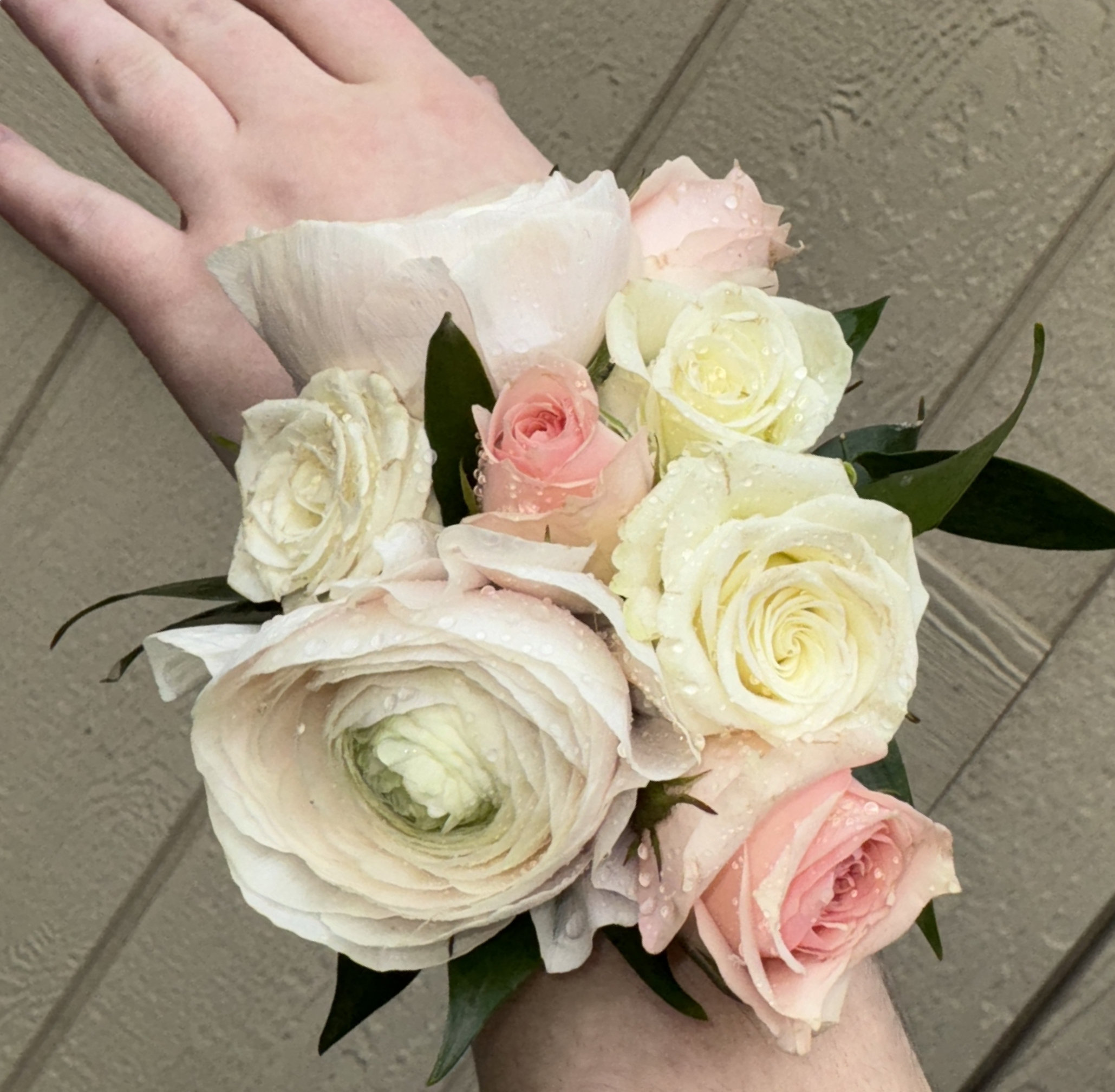 Small bouquet of pale pink and white roses and ranunculus in hand
