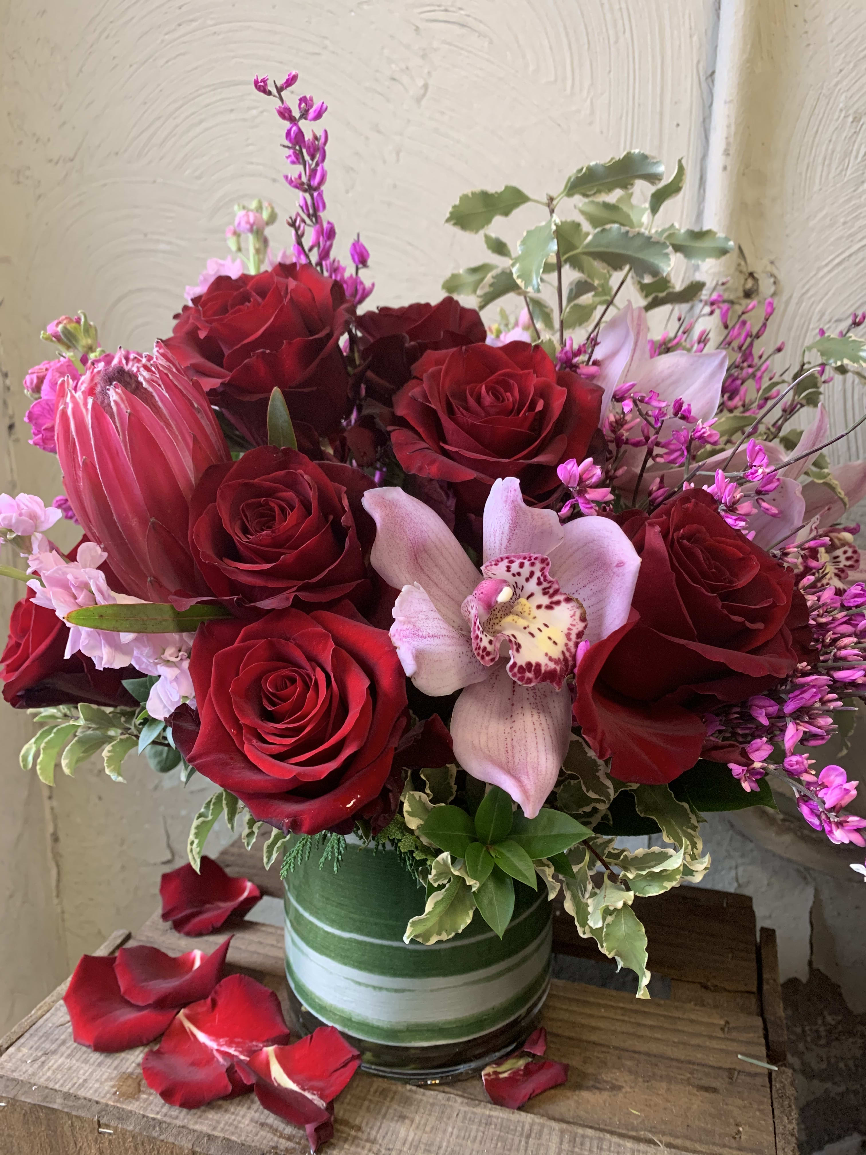 Red roses and a pale orchid in a green striped vase