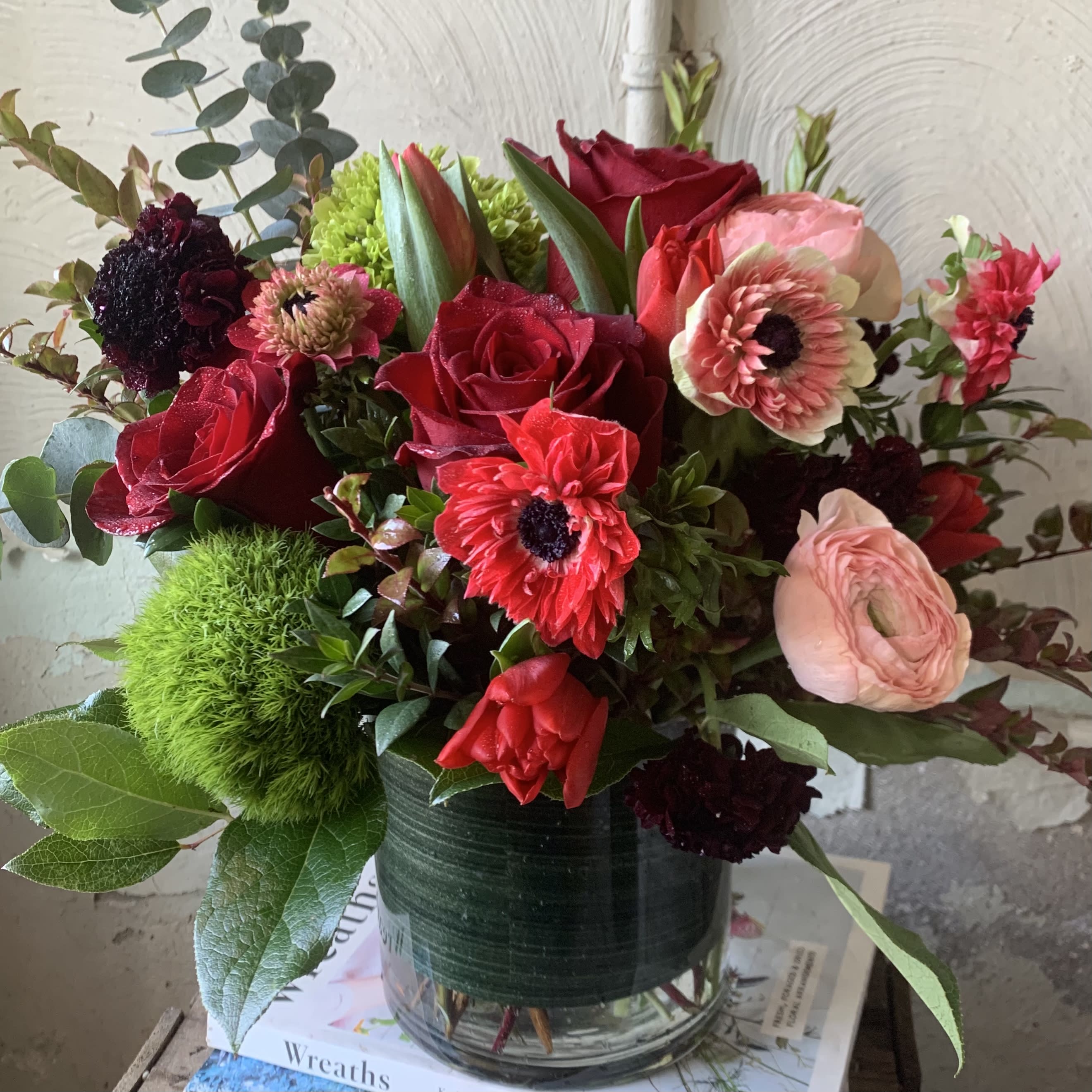 Red roses and pink blooms arranged in a glass vase