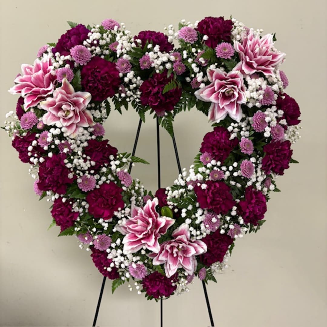 Heart-shaped floral wreath with pink and purple flowers on a stand