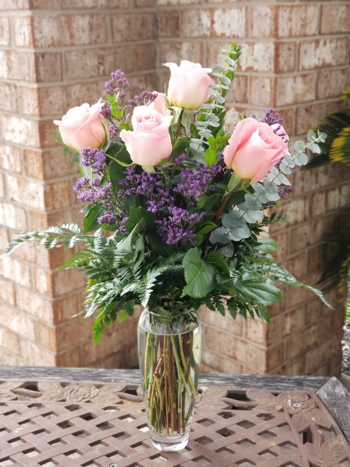 Pink roses and purple filler flowers in a clear glass vase