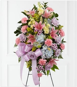 Blessings - Express your heartfelt condolences with our stunning standing spray featuring a captivating combination of pink lilies, blue hydrangea, purple roses, purple cushion daisies, pink carnations, yellow stock, lush greenery, and delicate filler flowers.