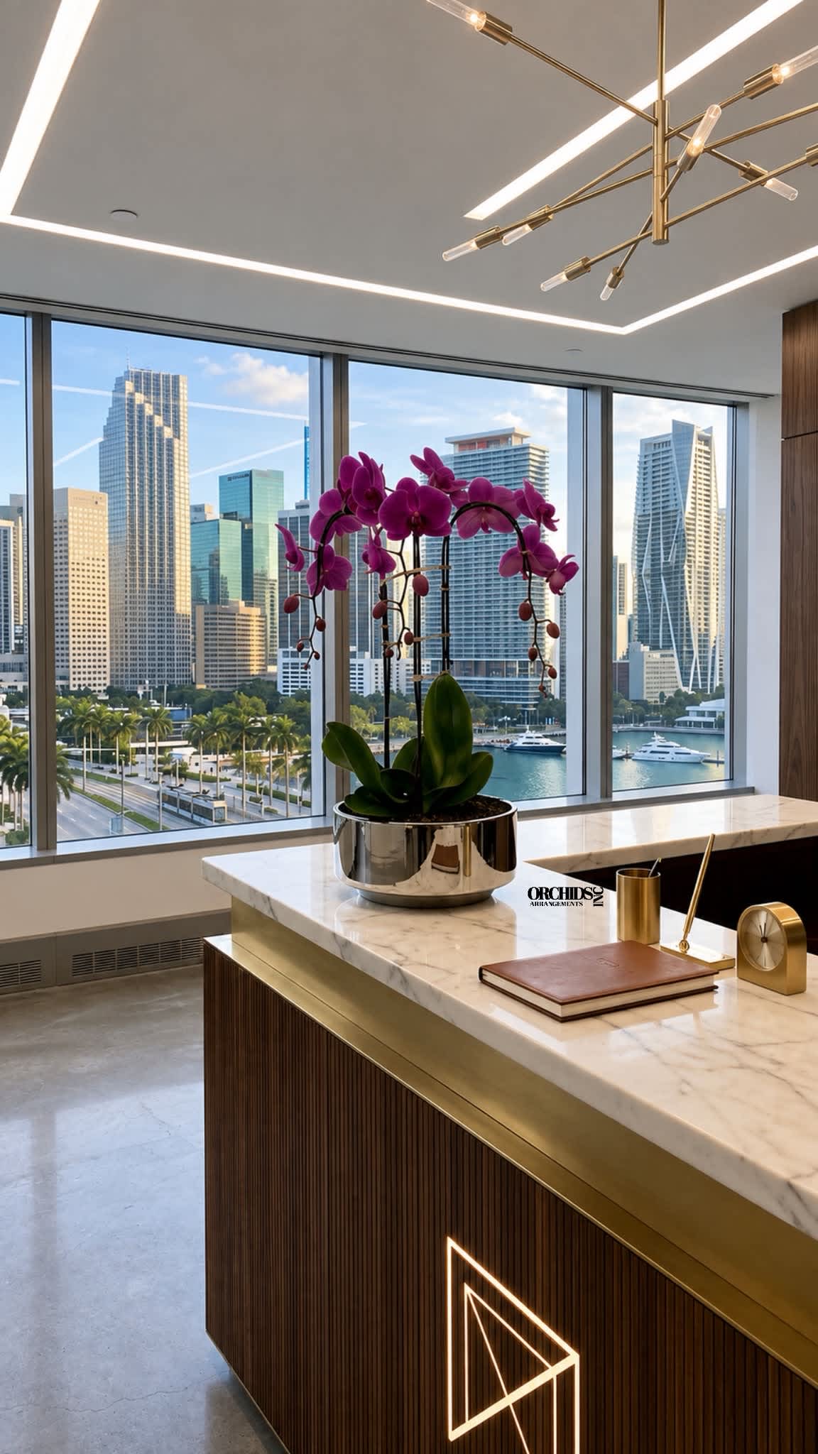 Potted purple orchid arrangement in a metallic planter on a marble desk
